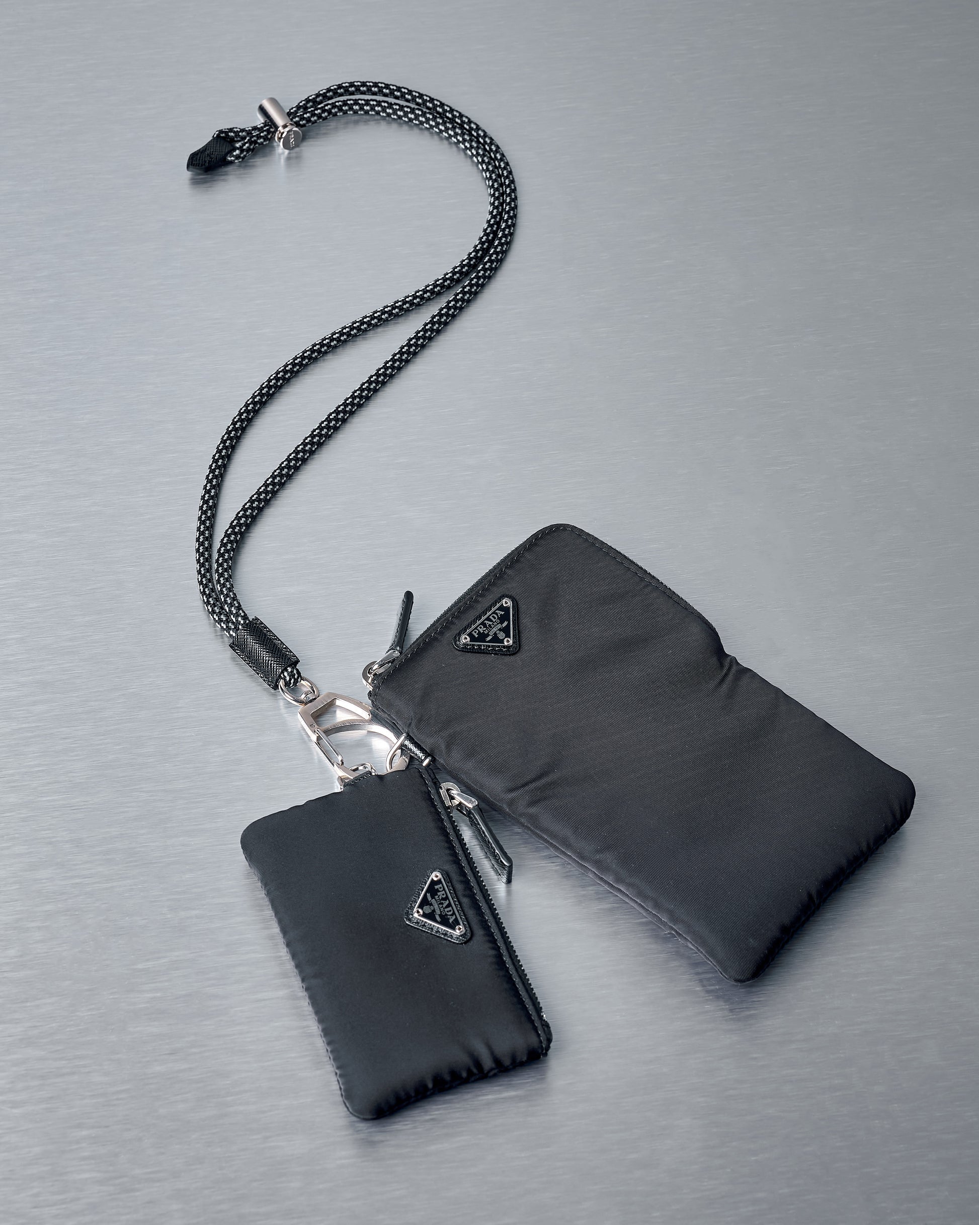 Black wallet and cardholder set with Prada logo on a grey background