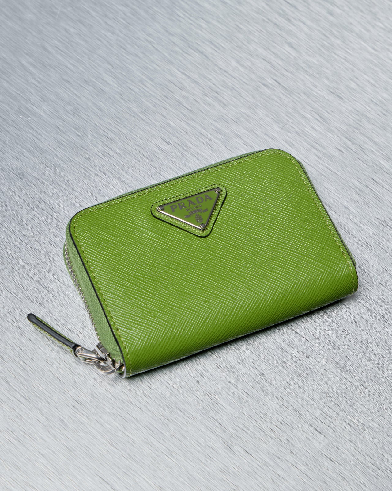 Green Prada wallet with a brand logo on a gray textured background