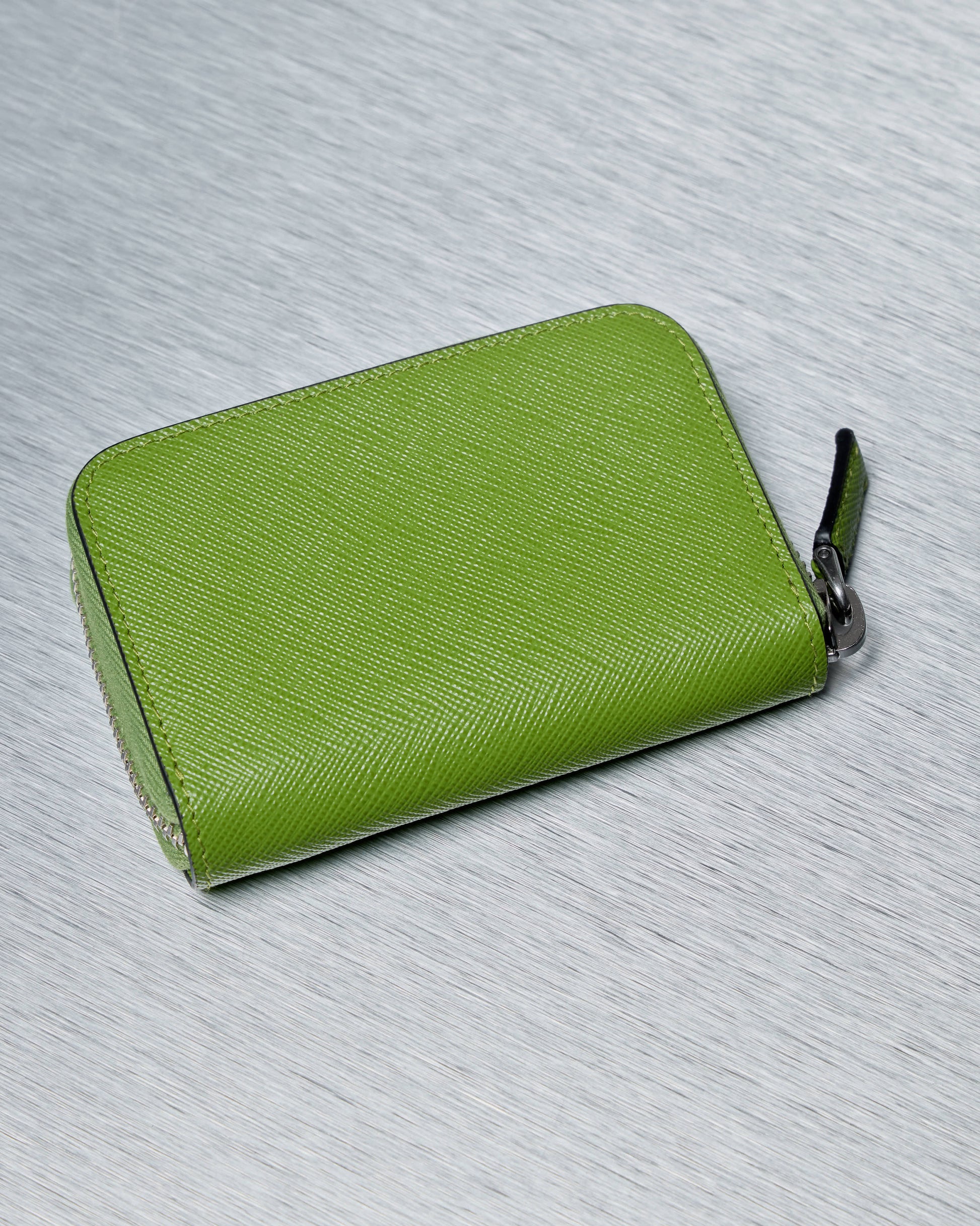Green Prada wallet with a zipper on a light gray background