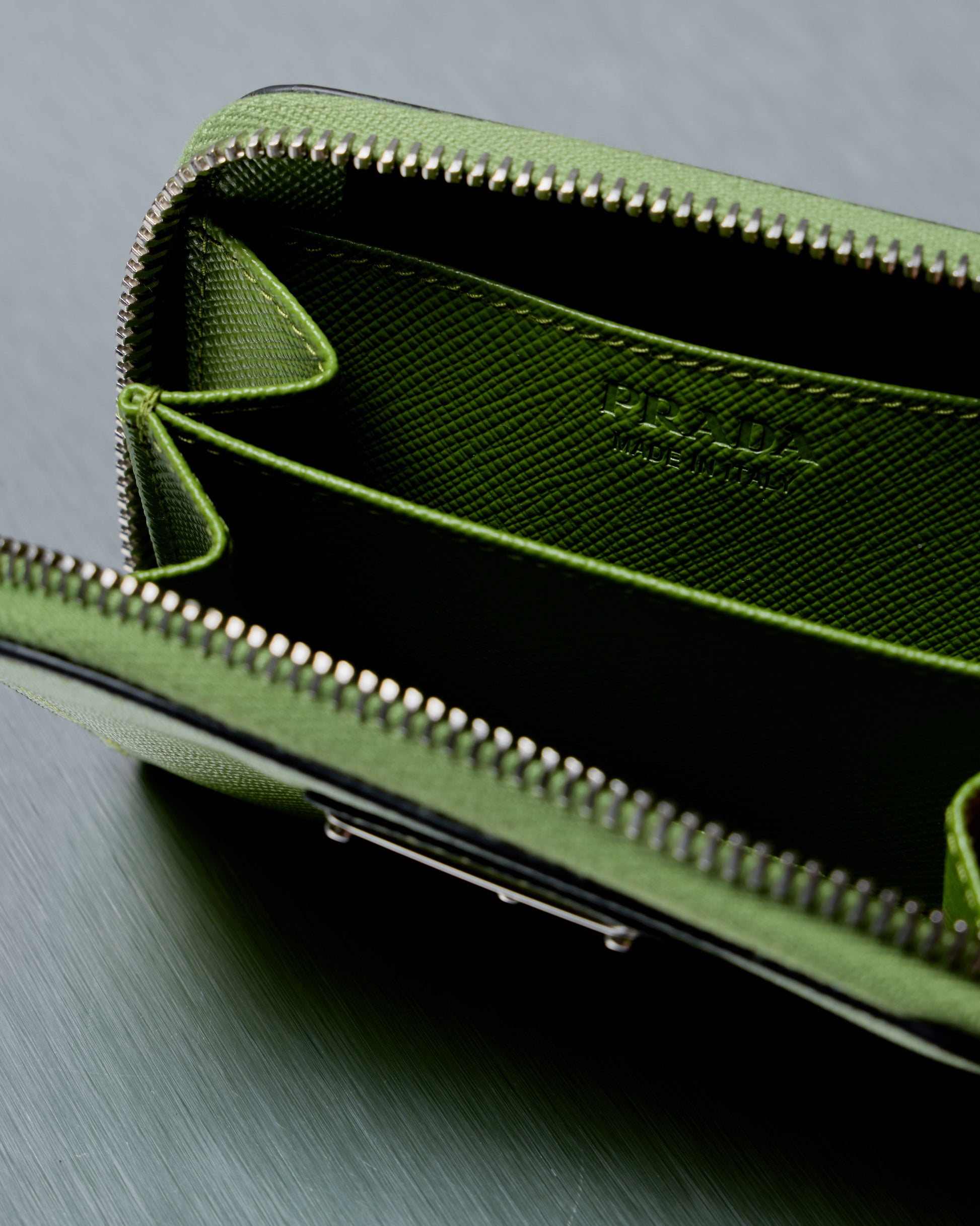 Green Prada wallet with Prada logo on a gray background