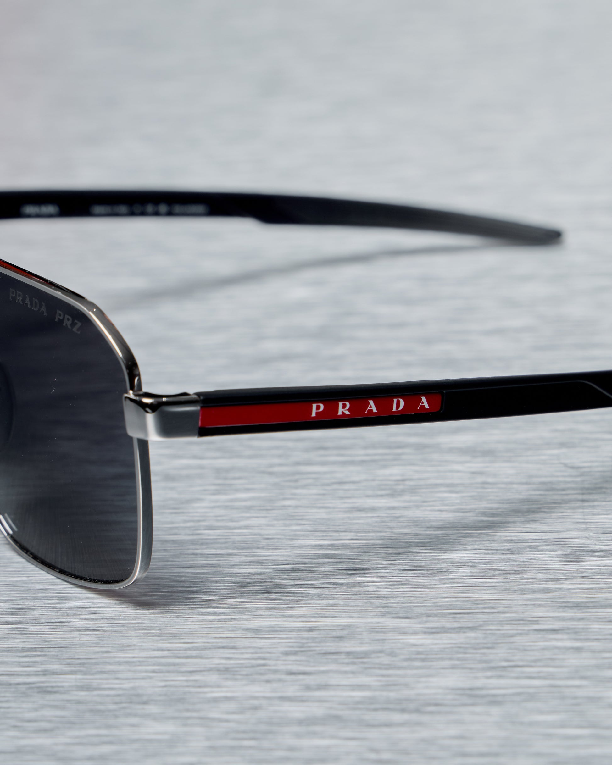 Prada sunglasses with black frame and red accents on a light gray background