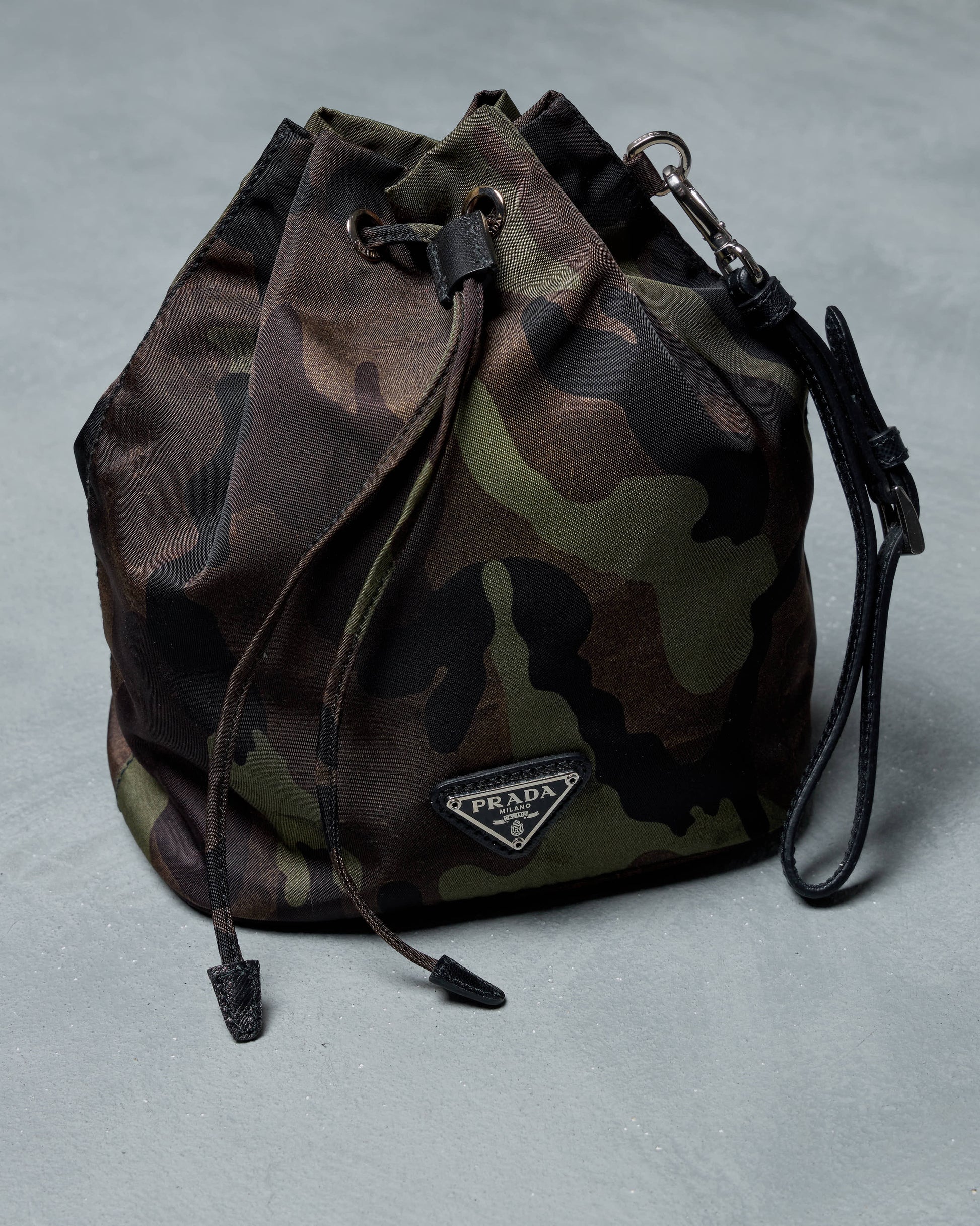 Camouflage drawstring bag with Prada logo on a gray background