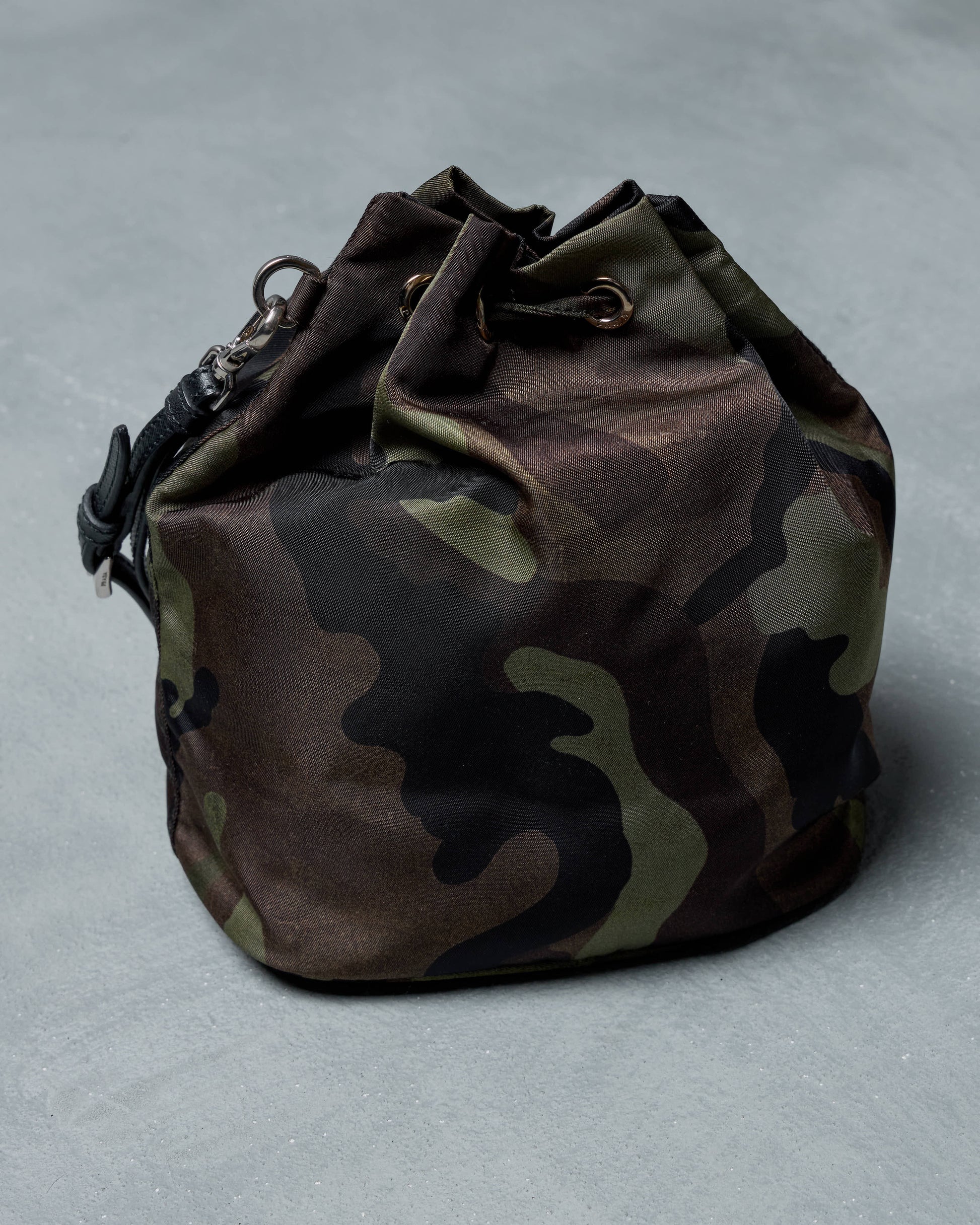 Camouflage drawstring Prada wrist bag on a light gray background