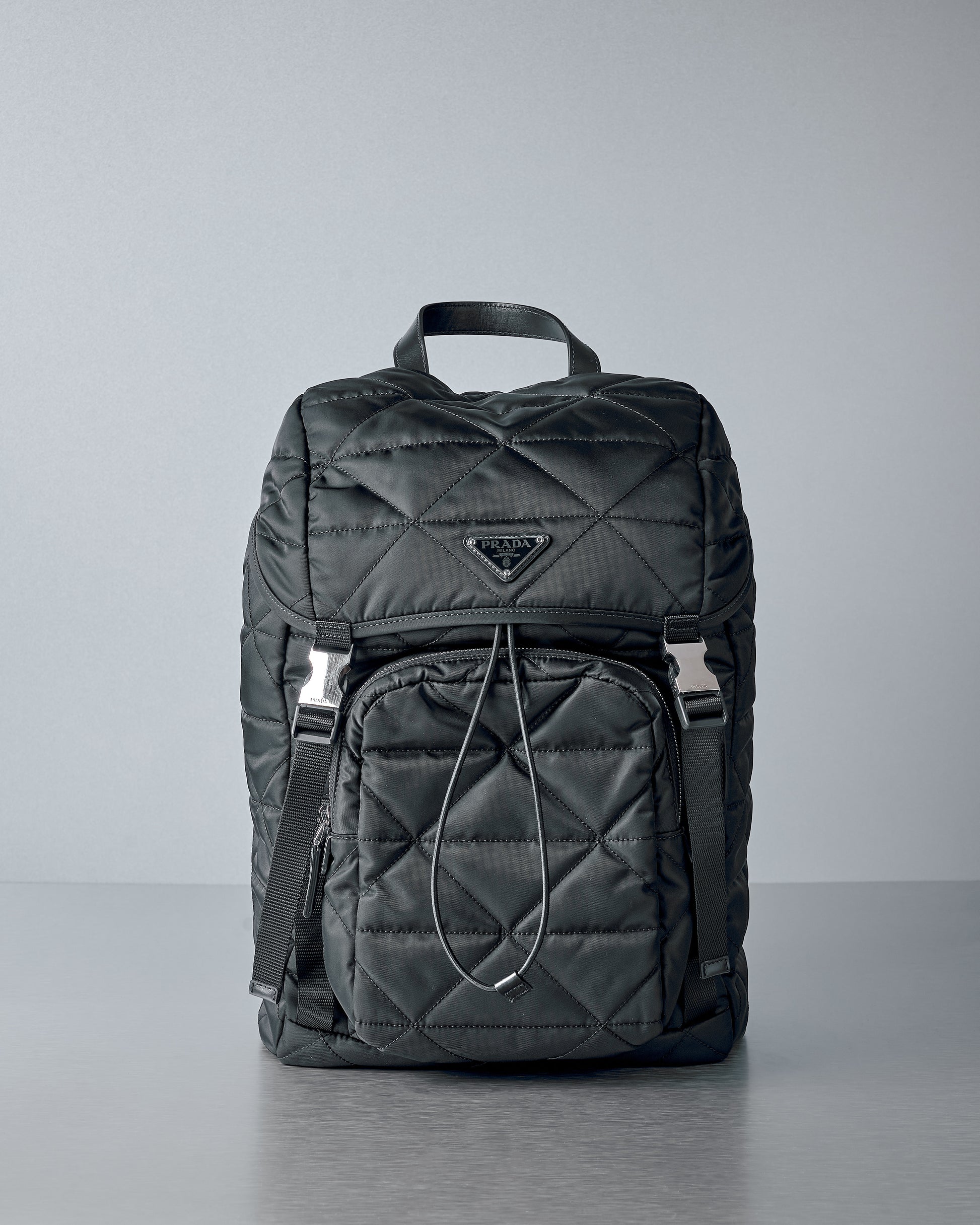 Black quilted  Prada backpack on a grey background