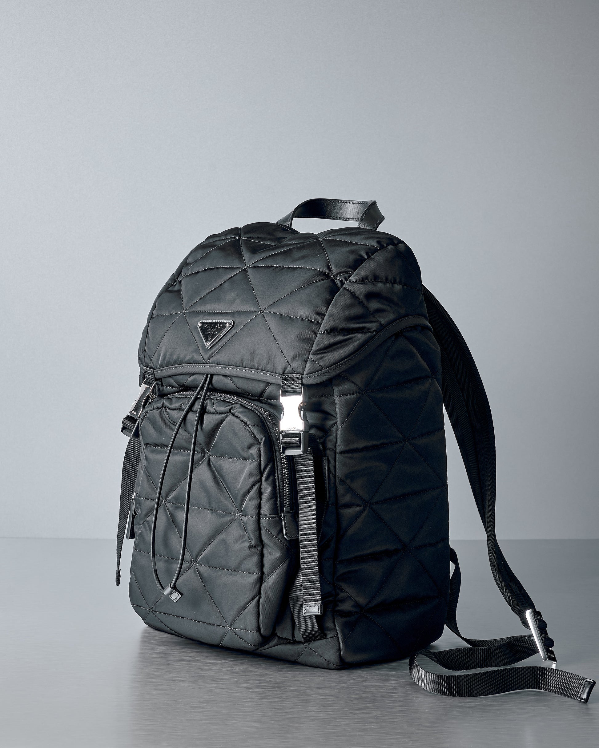 Black quilted Prada backpack on a grey background