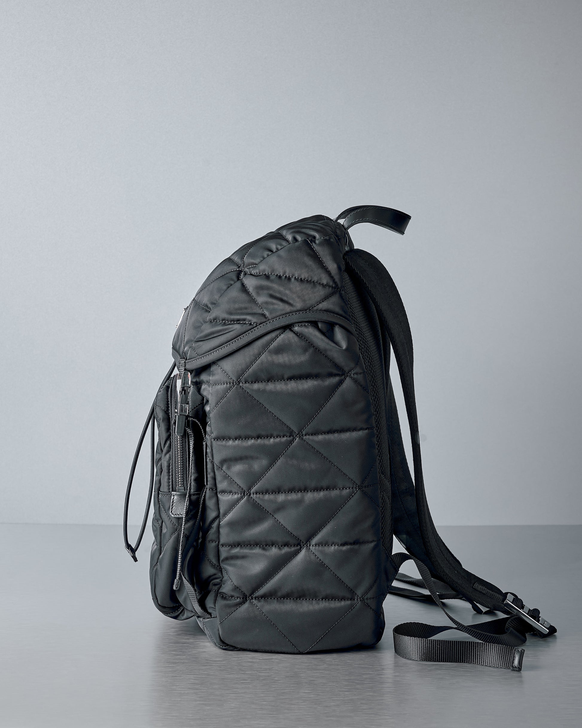 Black quilted Prada backpack on a grey background