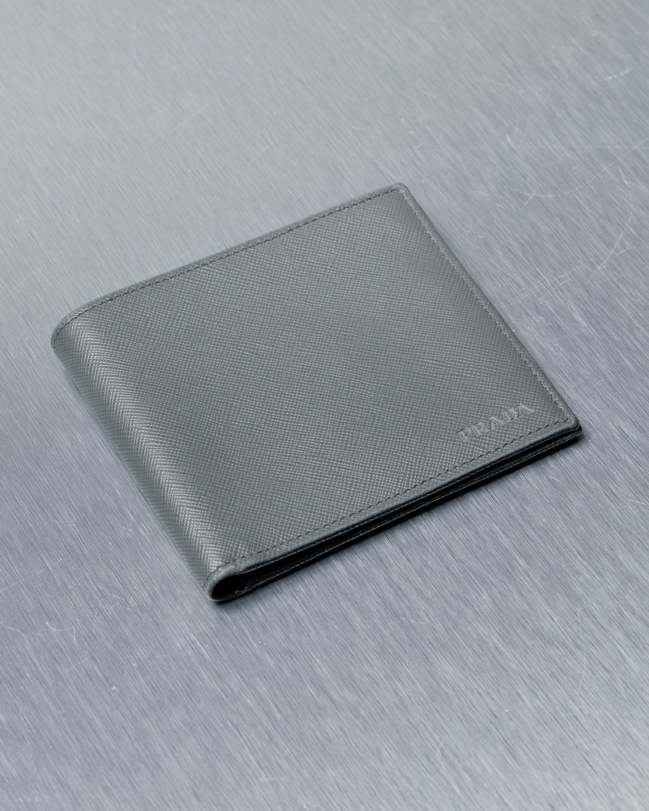 Gray Prada wallet on a textured gray surface