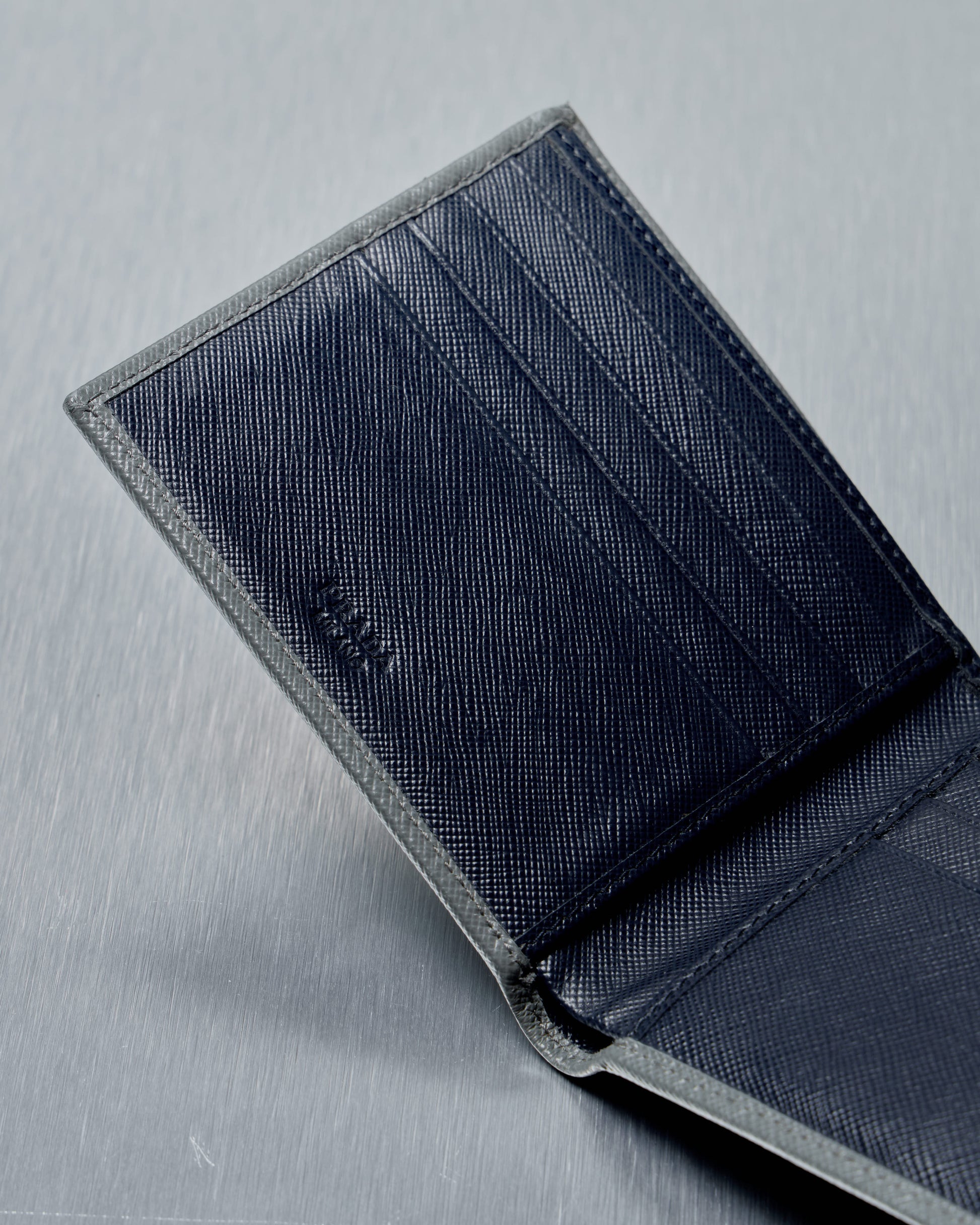 Navy blue Prada wallet on a gray background