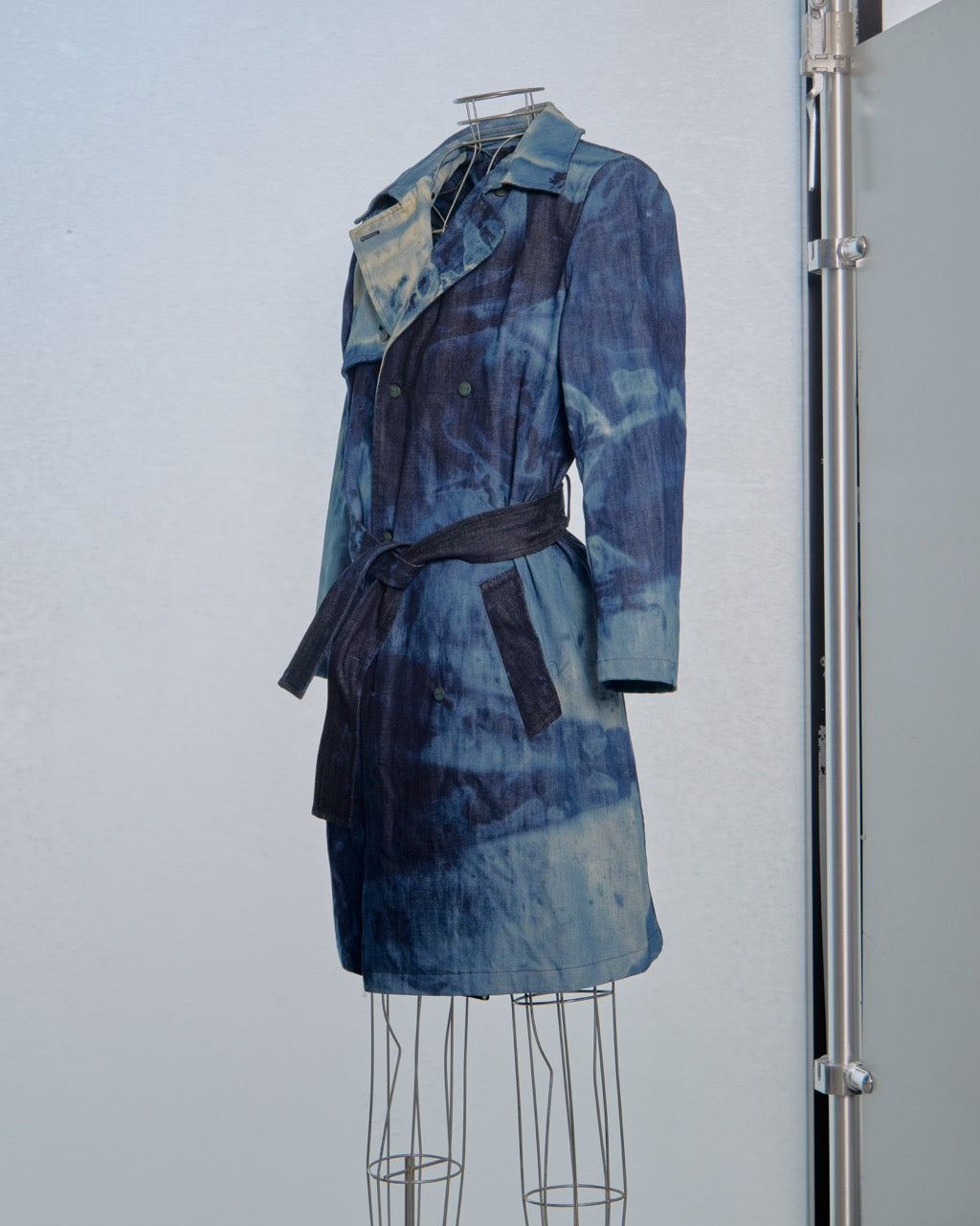 Blue tie-dye Raf Simons coat on a mannequin against a white background