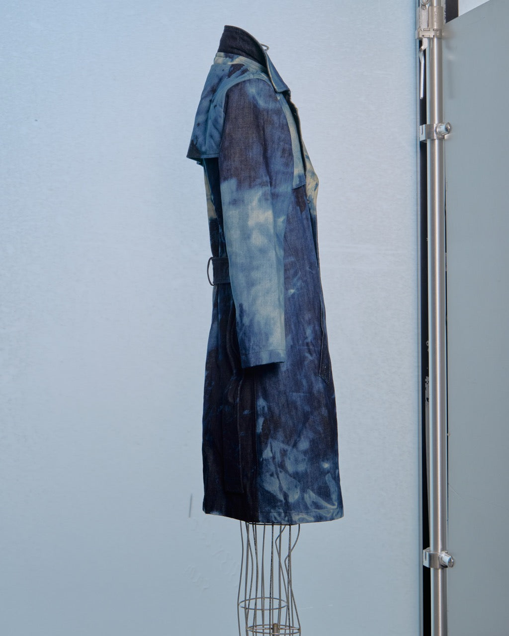 Blue patterned Raf Simons coat on a mannequin against a light gray background