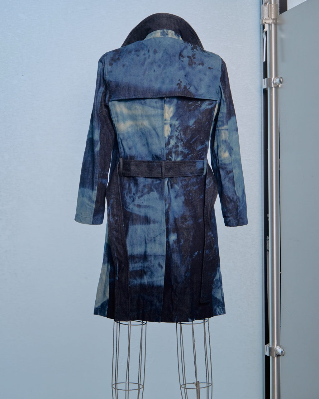 Blue tie-dye Raf Simons coat on a mannequin against a light blue background