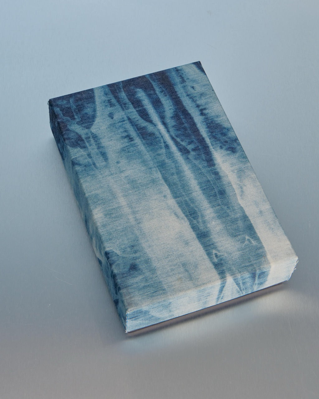 Raf Simons garment box with blue and white marbled cover on a gray background