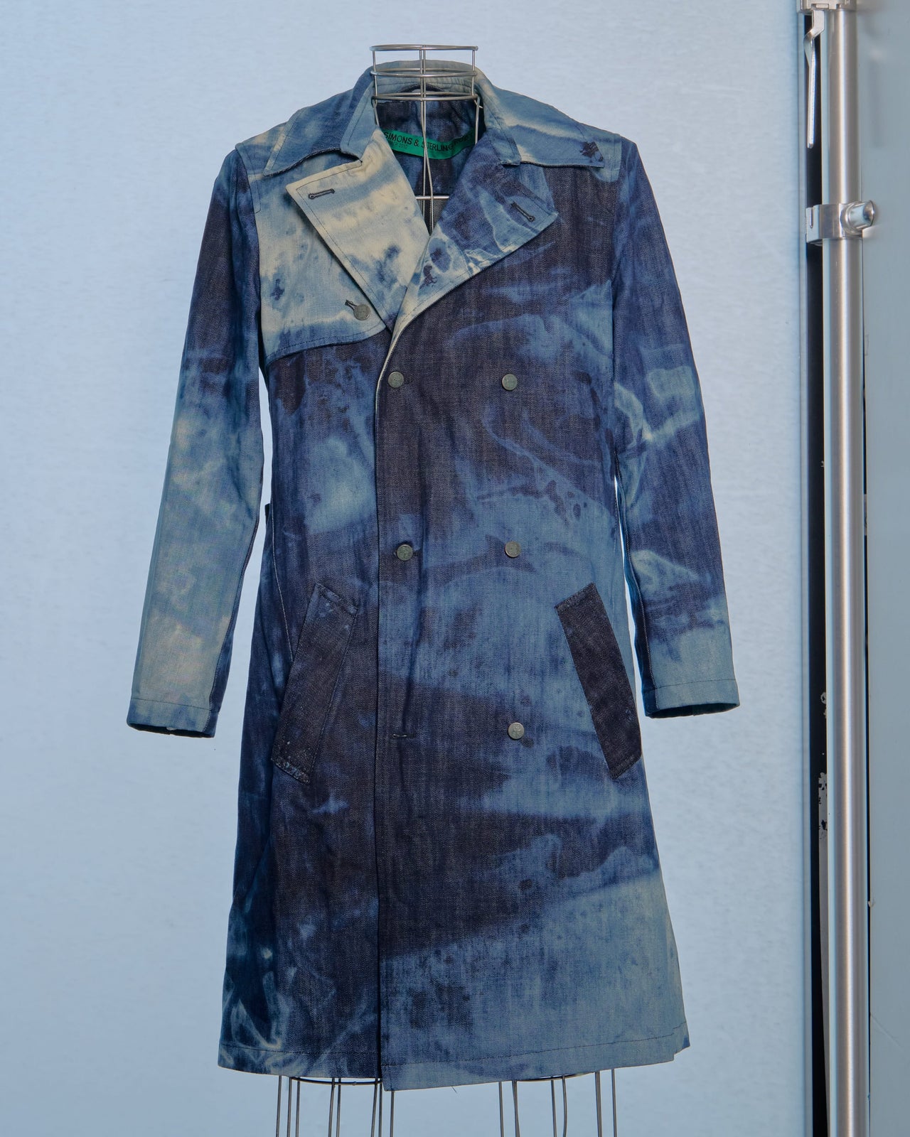 Blue patterned Raf Simons x Sterling Ruby coat on a mannequin against a light blue background
