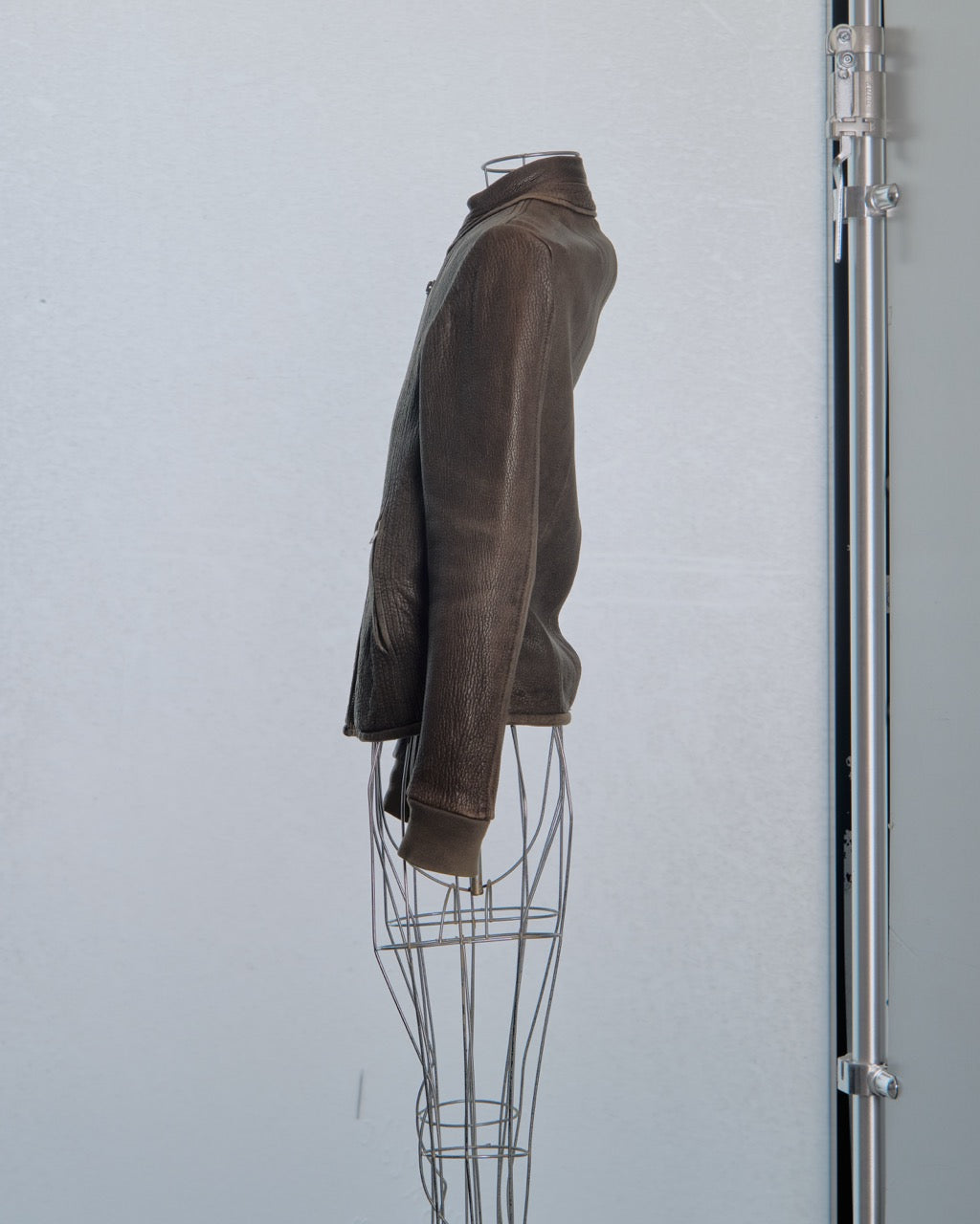 Brown leather Rick Owens jacket on a wire mannequin against a light gray background