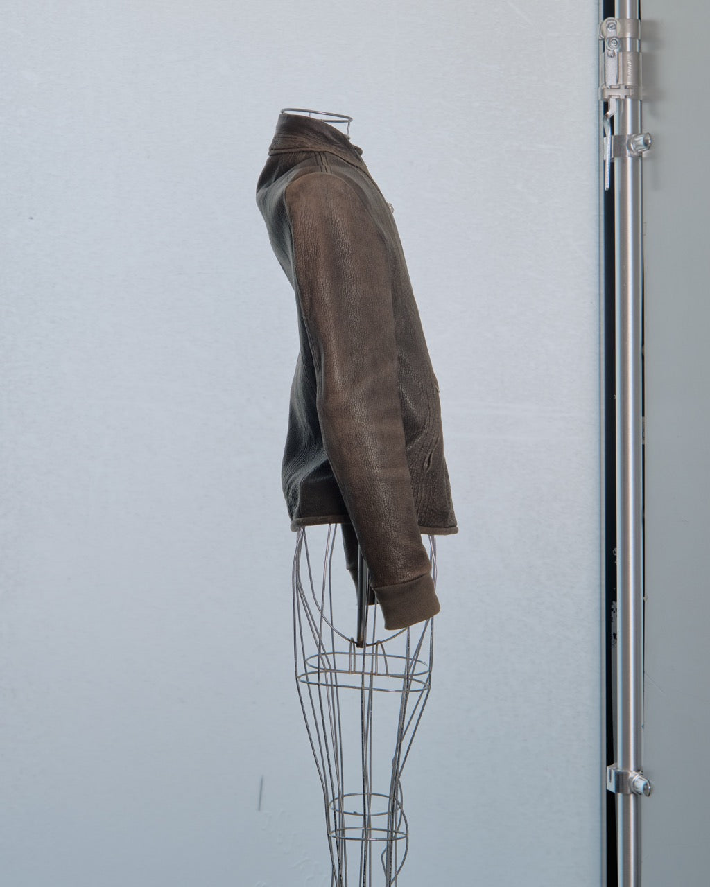 Brown leather jacket Rick Owens on a wire mannequin against a light gray background