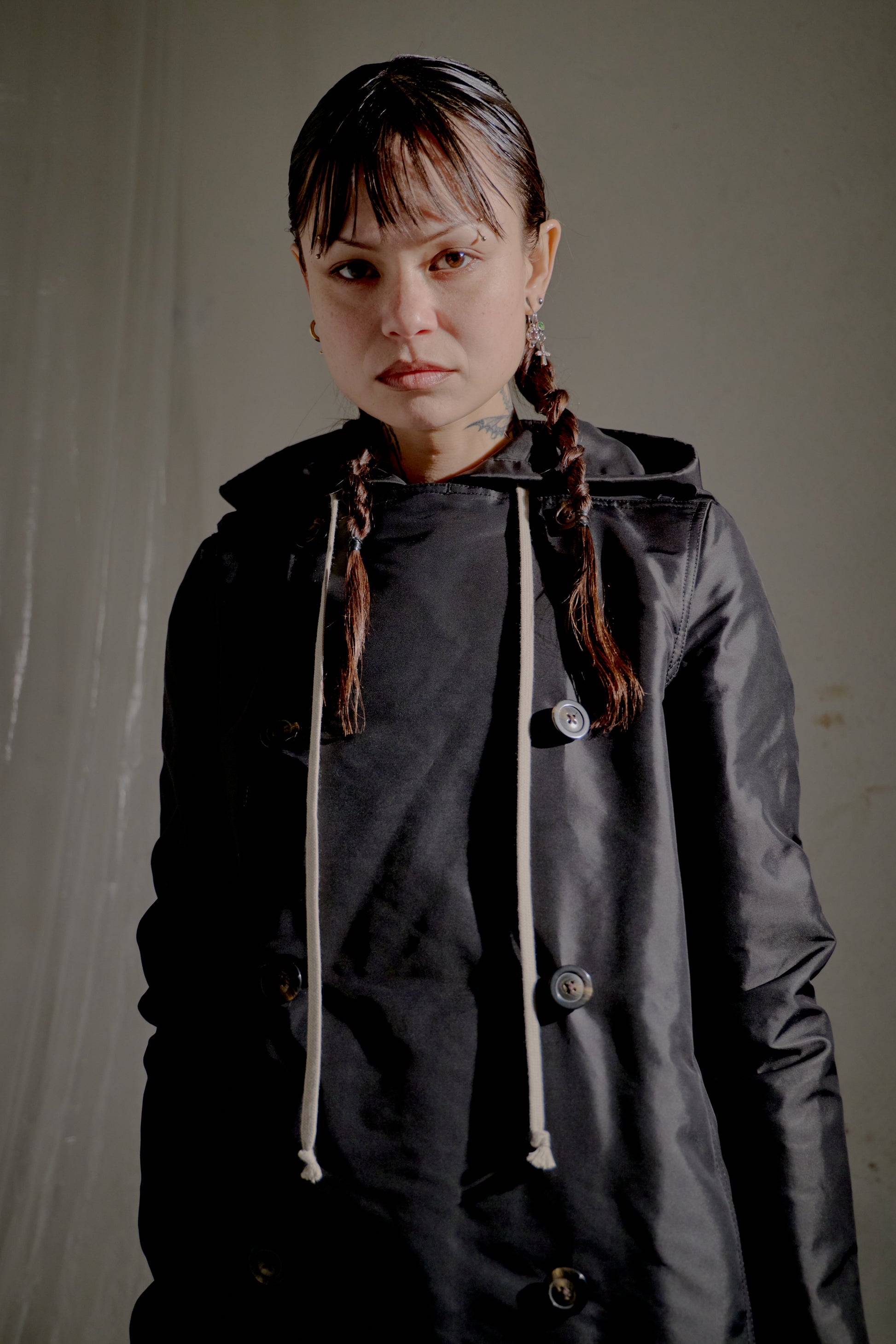 Person wearing a black hooded Rick Owens jacket with a plain background