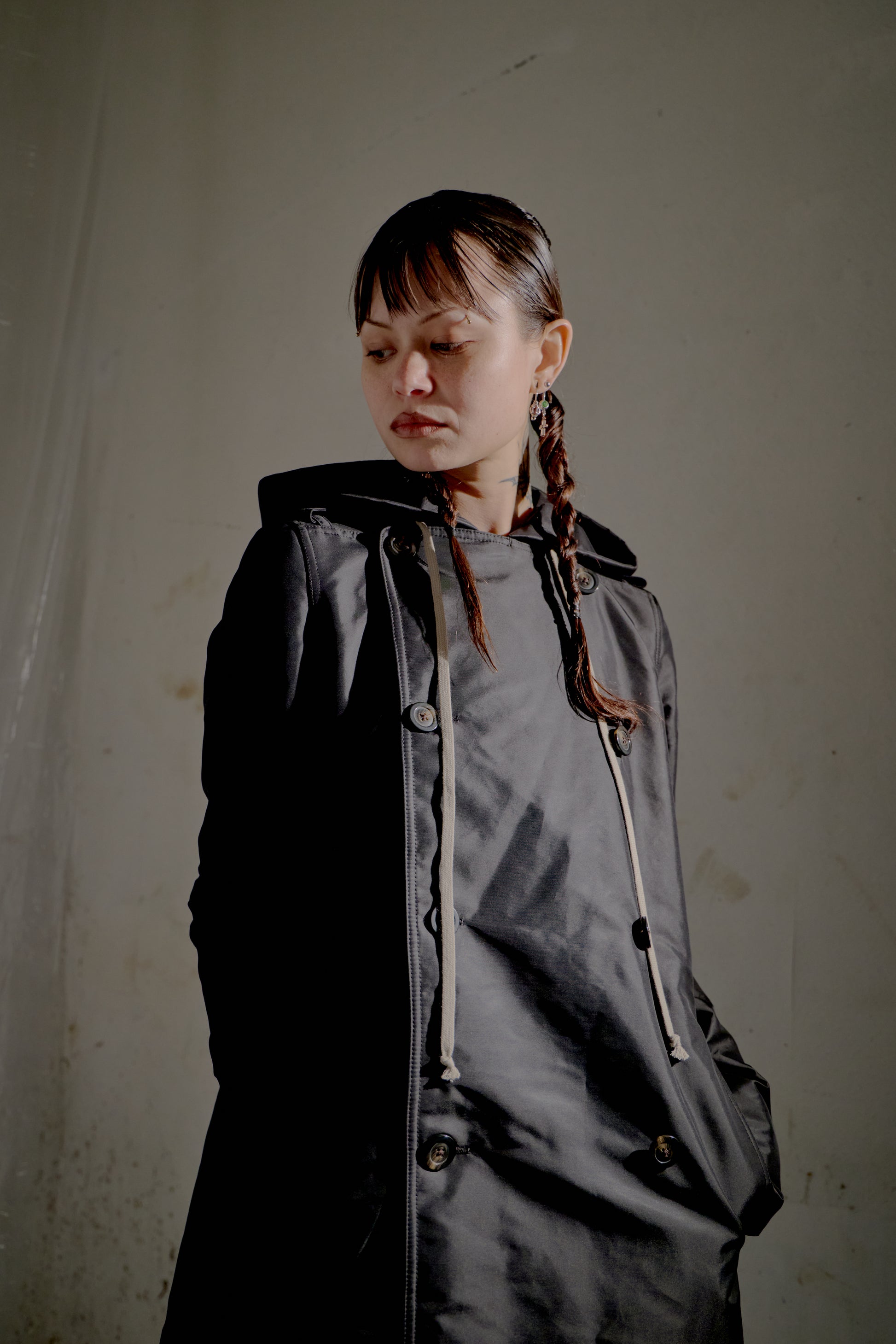 Person wearing a dark black Rick Owens raincoat against a plain background