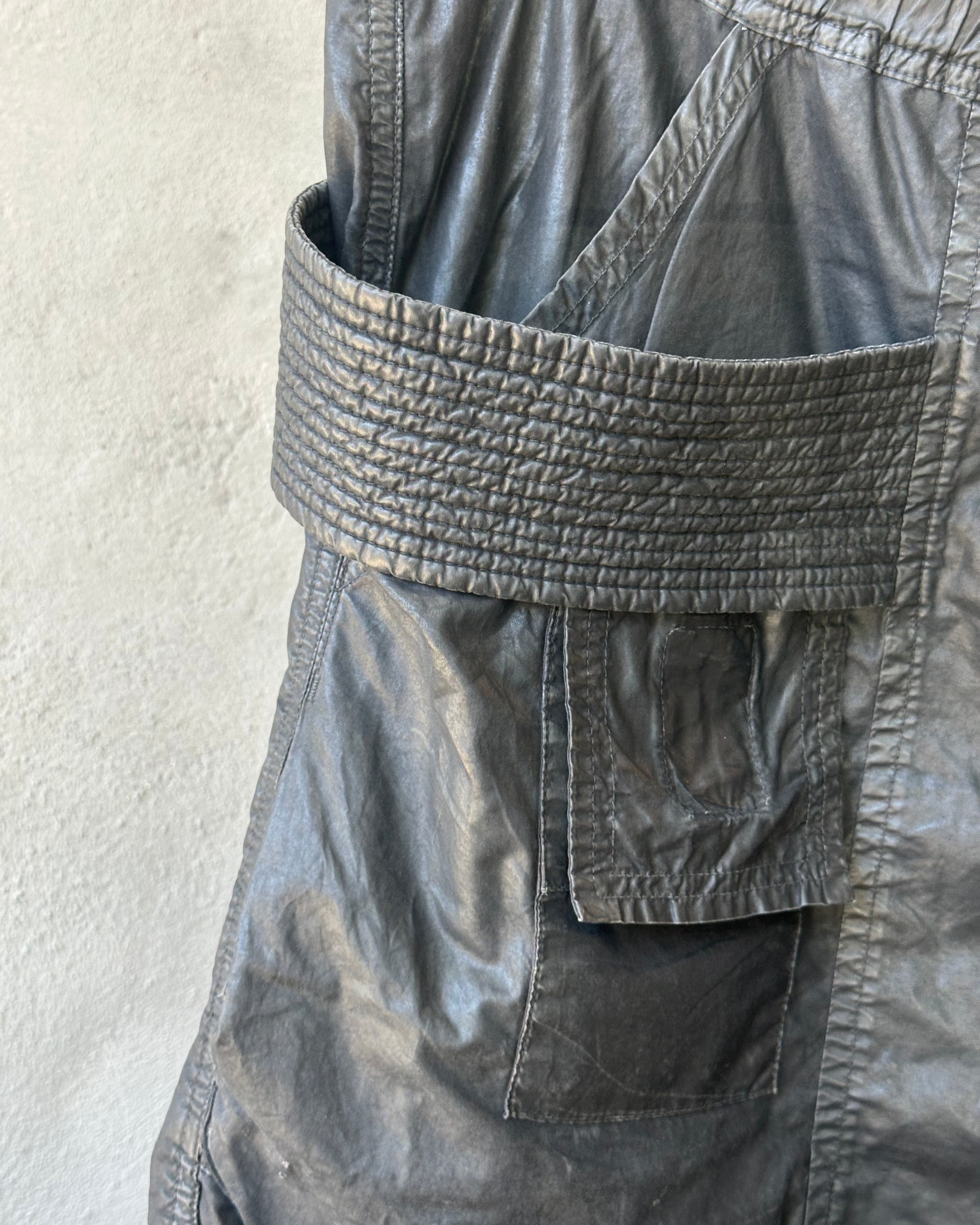 Close-up of a dark gray Rick Owens cargo pants with a textured belt against a light background