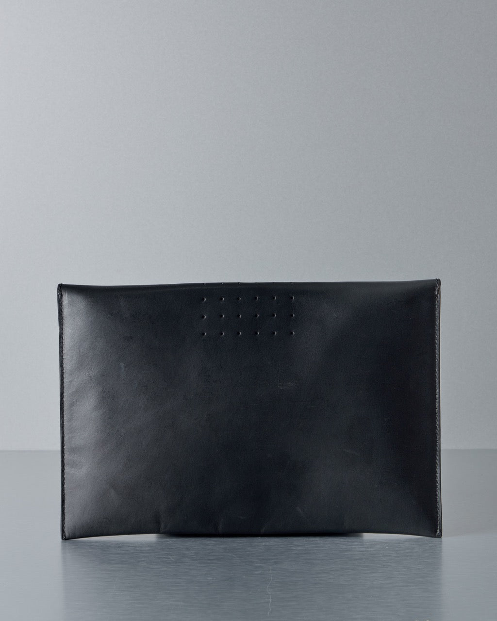 Black leather Rick Owens pouch on a reflective surface with a gray background