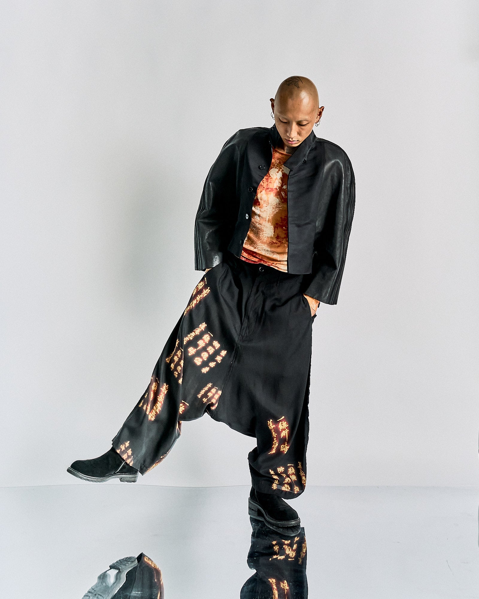 Person modelling in a sleek black Rick Owens outfit with a cropped jacket and loose pants featuring abstract patterns. 