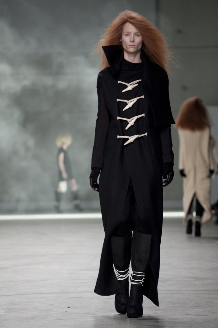 Model wearing a black Rick Owens outfit with unique design elements on a runway.