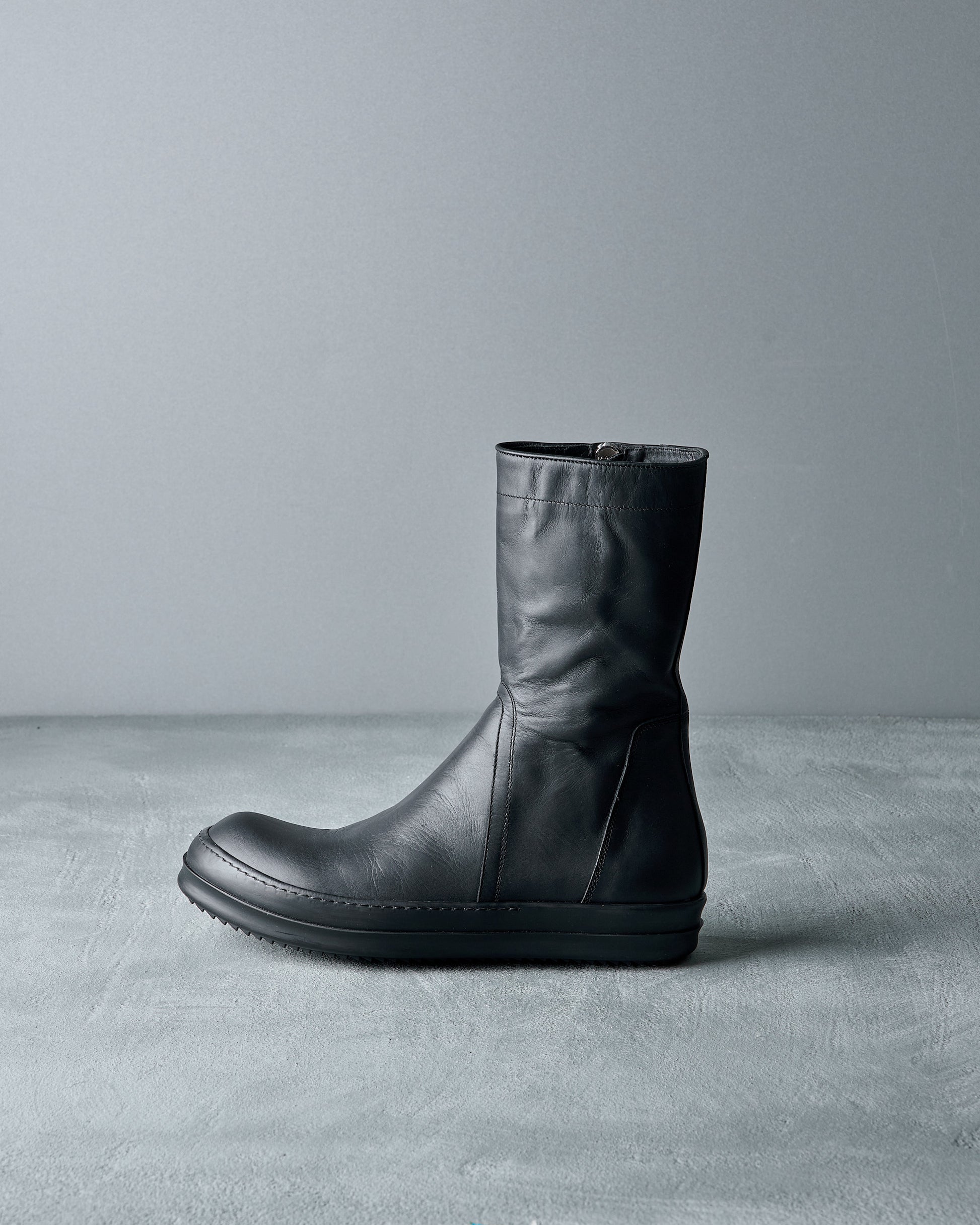Black leather Rick Owens boot on a gray background