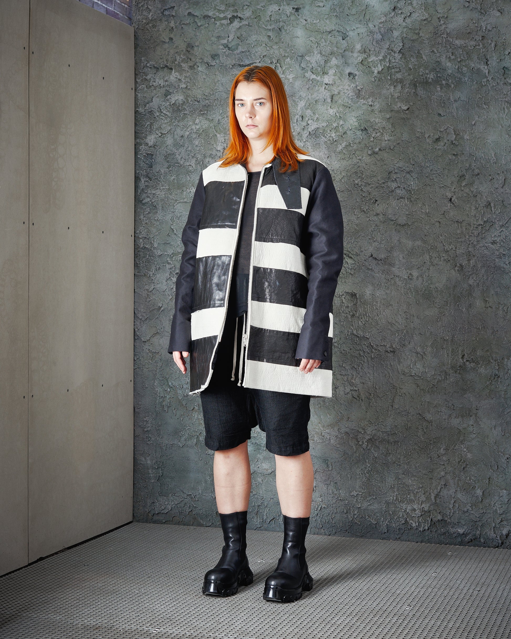 A model wearing a black and white striped panel jacket with a high collar and long fit, from the Rick Owens FW 2017 collection.