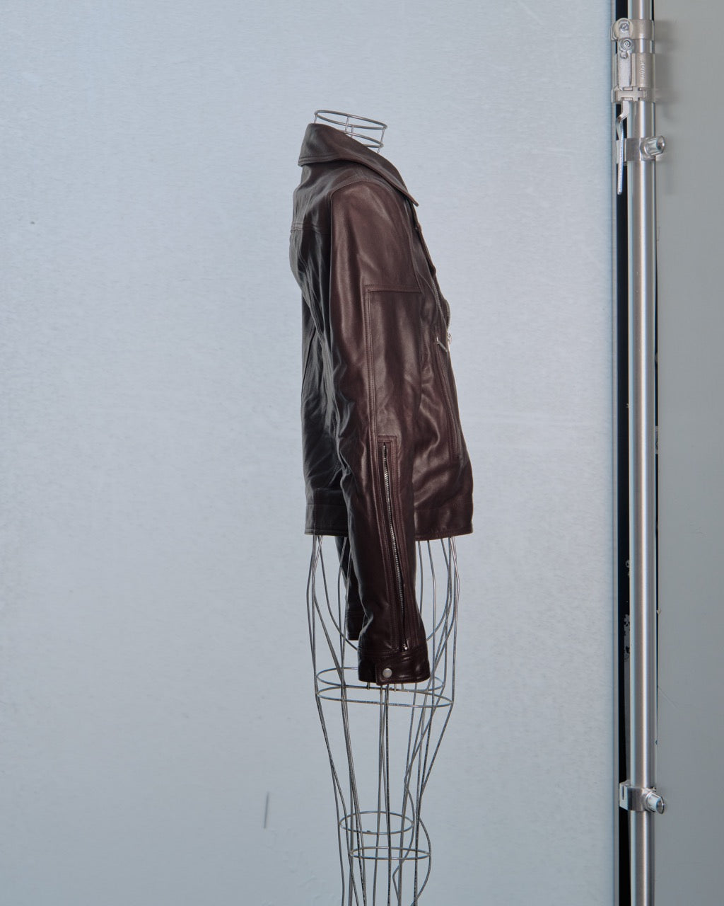 Brown leather Rick Owens jacket on a wire mannequin against a light gray background