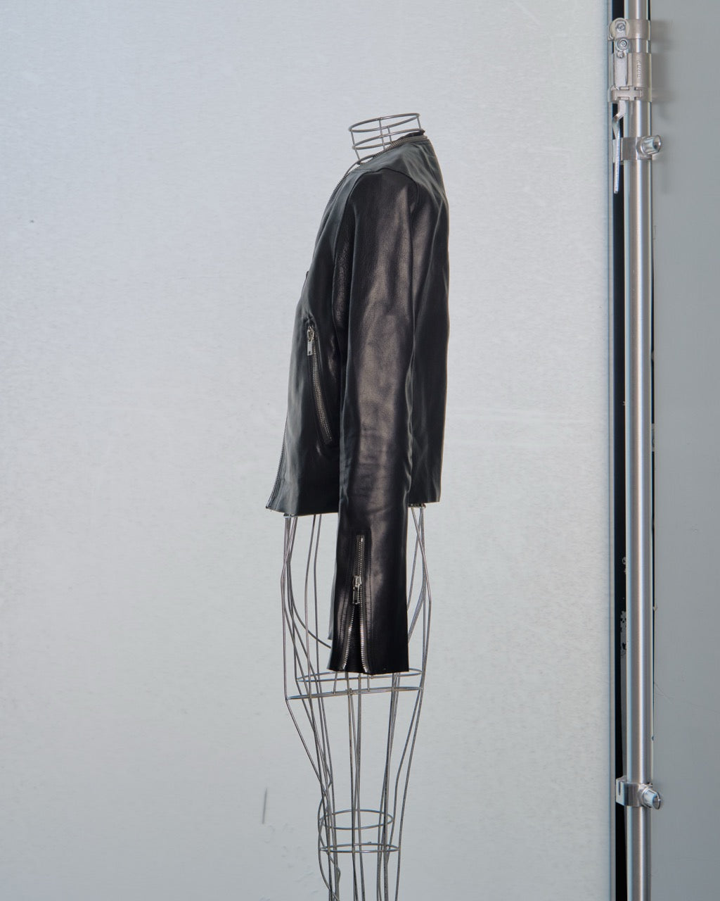 Black leather Rick Owens jacket on a wire mannequin against a white wall