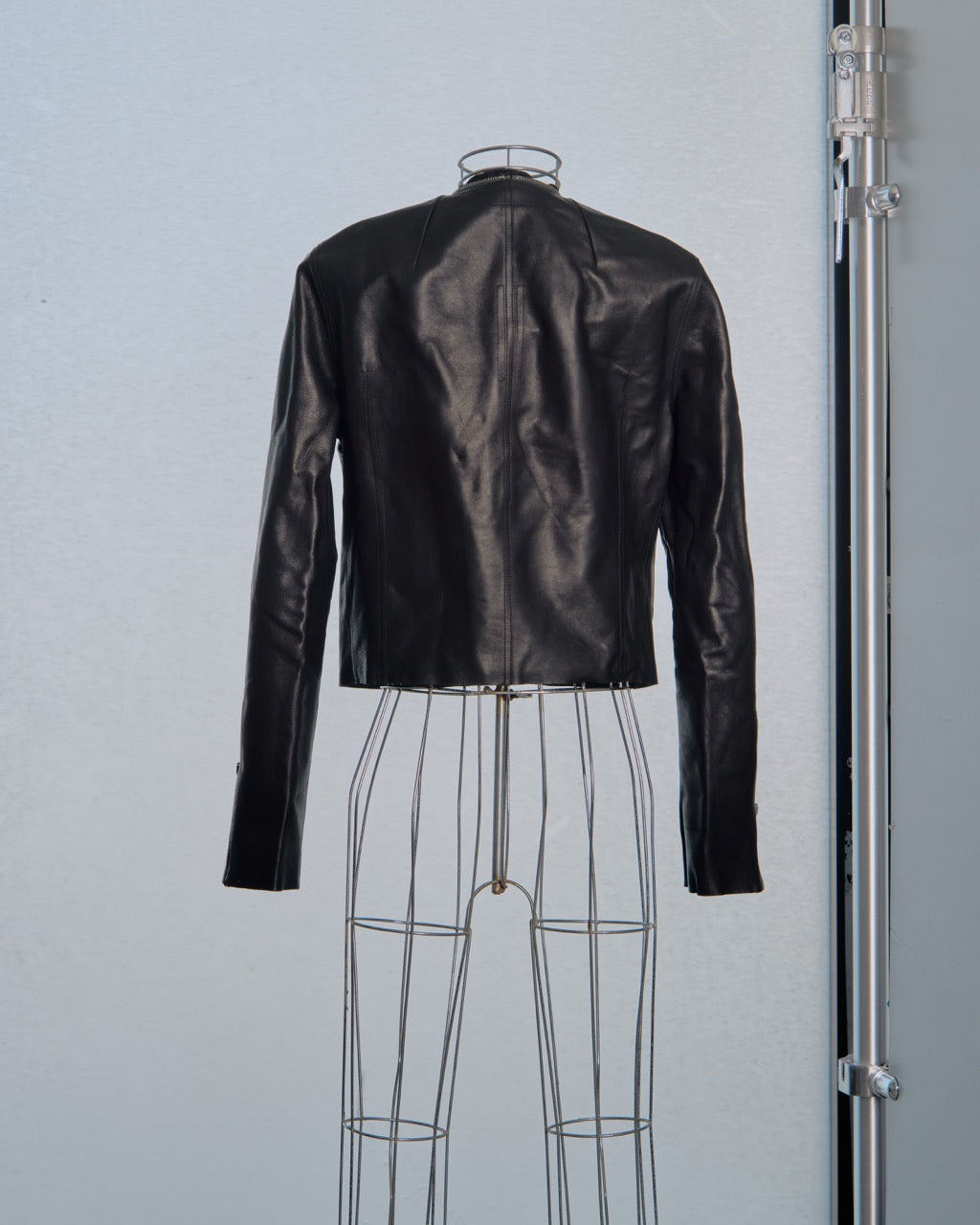 Black leather Rick Owens jacket on a wire mannequin against a light gray background