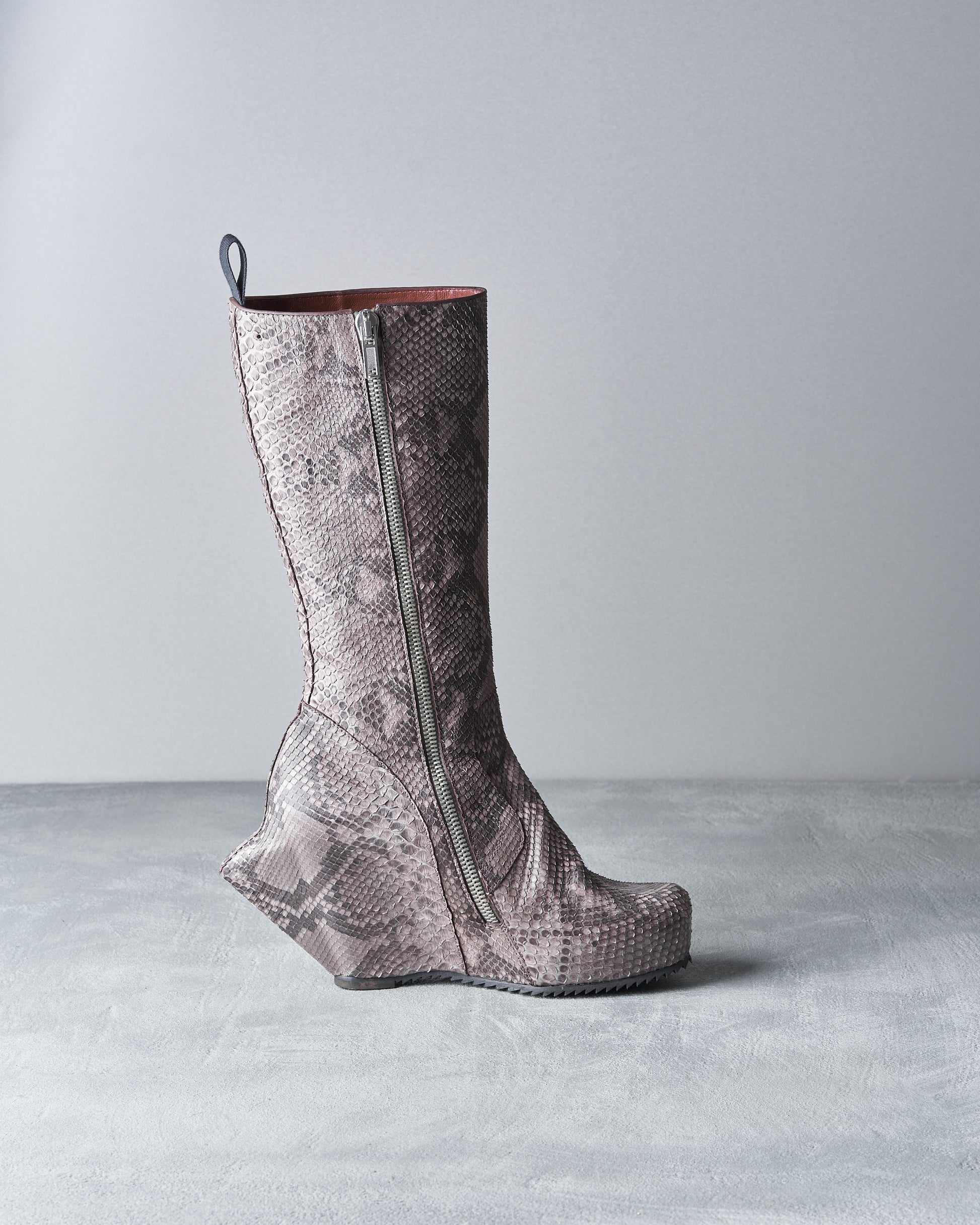 A high-heeled Rick Owens boot with a textured, snake-pattern design in grey tones.