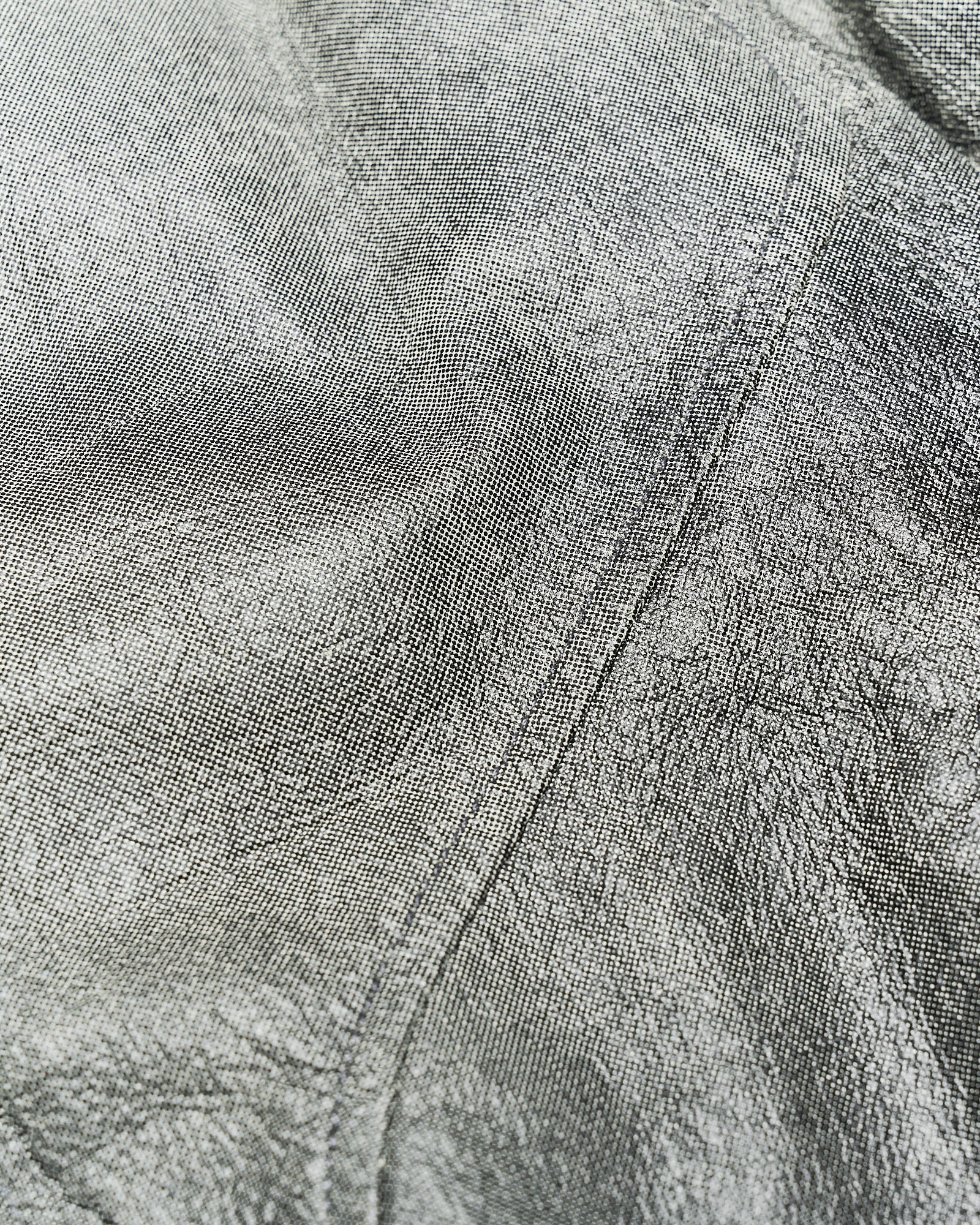 Close-up of a textured fabric from a Rick Owens jacket with fine, intricate lines creating a swirling pattern. The material appears soft and has a subtle grey tone.
