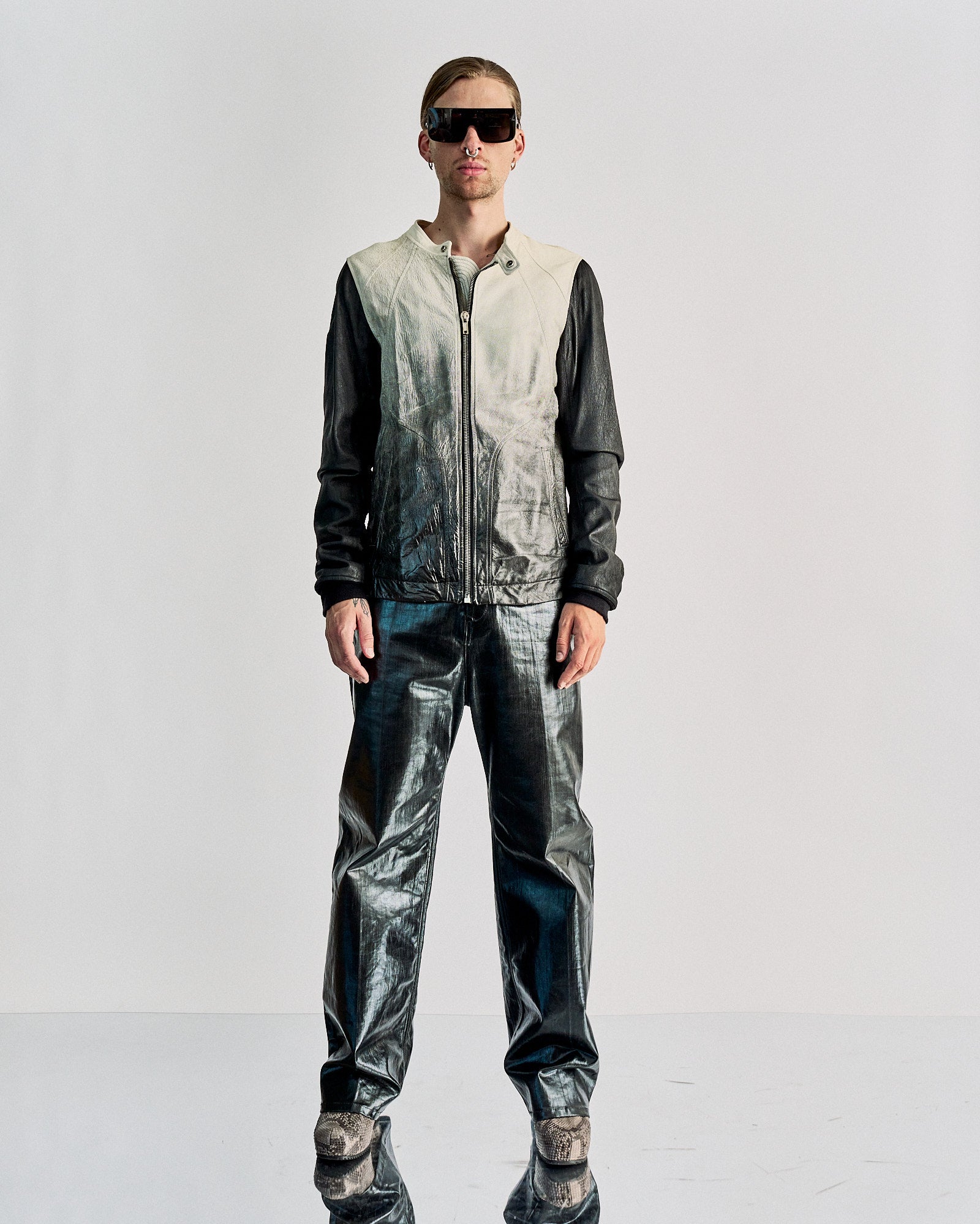A person wearing a Rick Owens SS 2009 Gradient leather bomber jacket with a moto-style snap button collar and front zip closure. The jacket is primarily black with a gradient design that transitions into a gloss finish, and features two front pockets.