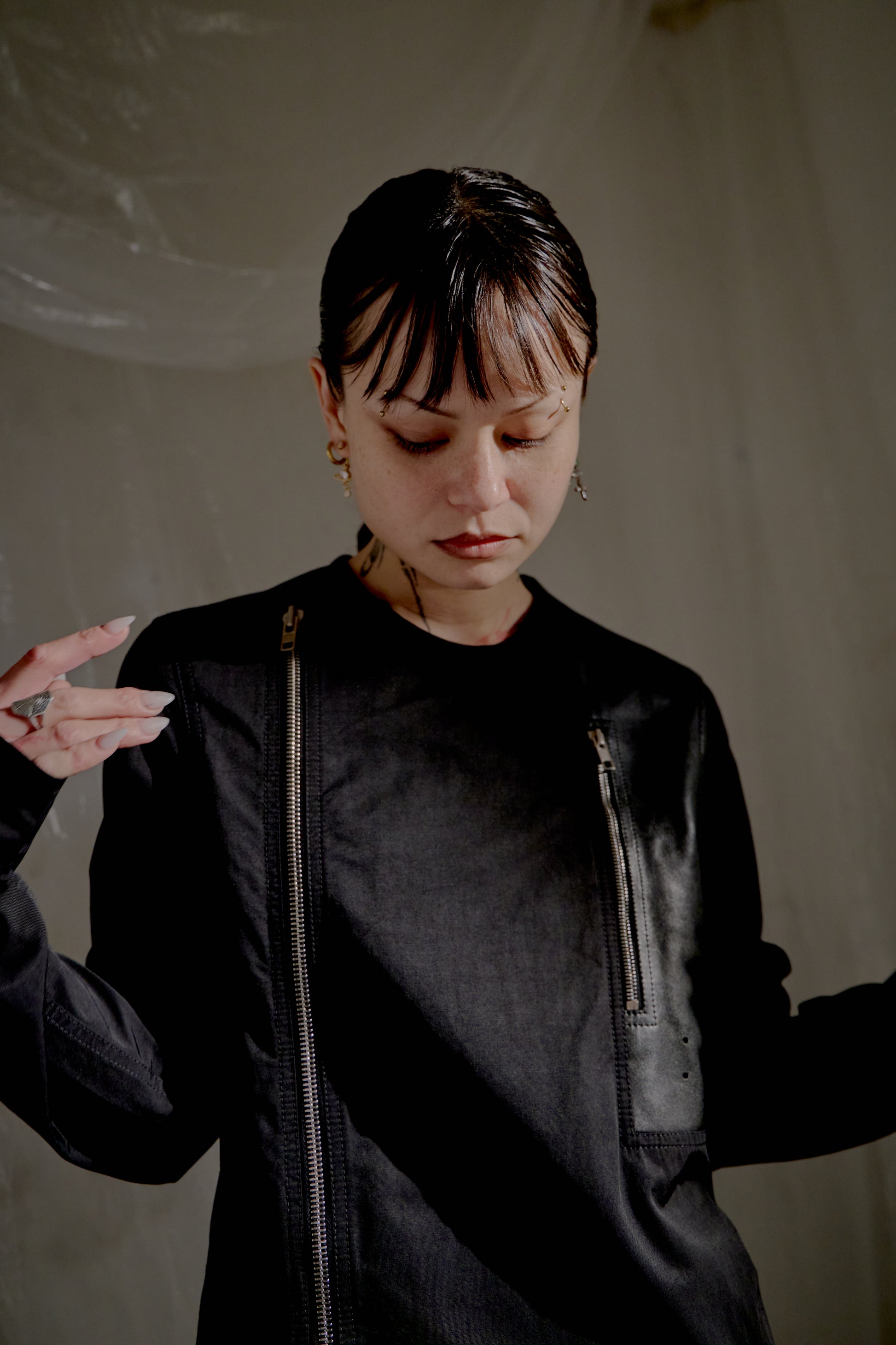 Person wearing a black Rick Owens jacket with a neutral background