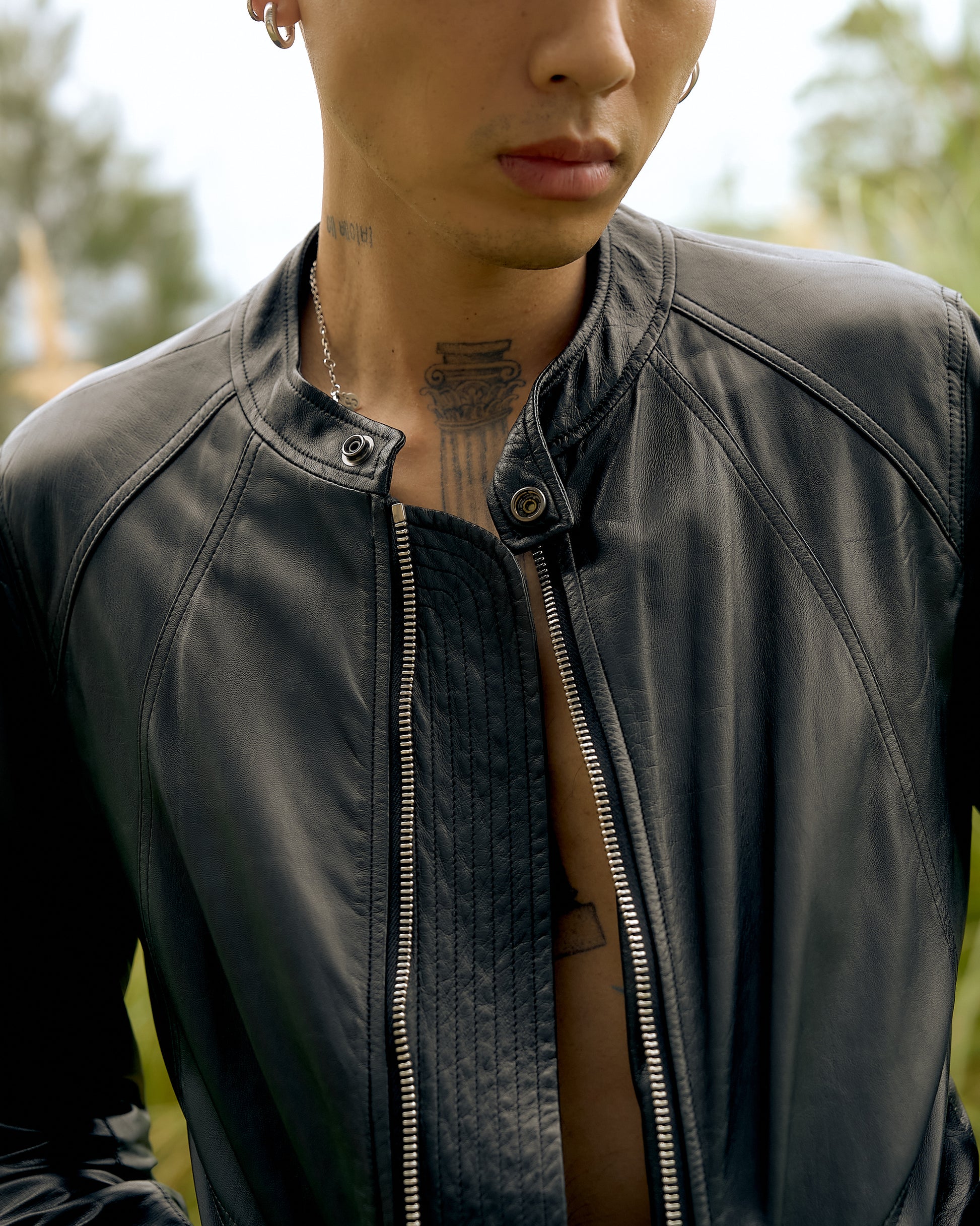 A close-up of a person wearing a black Rick Owens leather jacket with a visible zipper and collar.