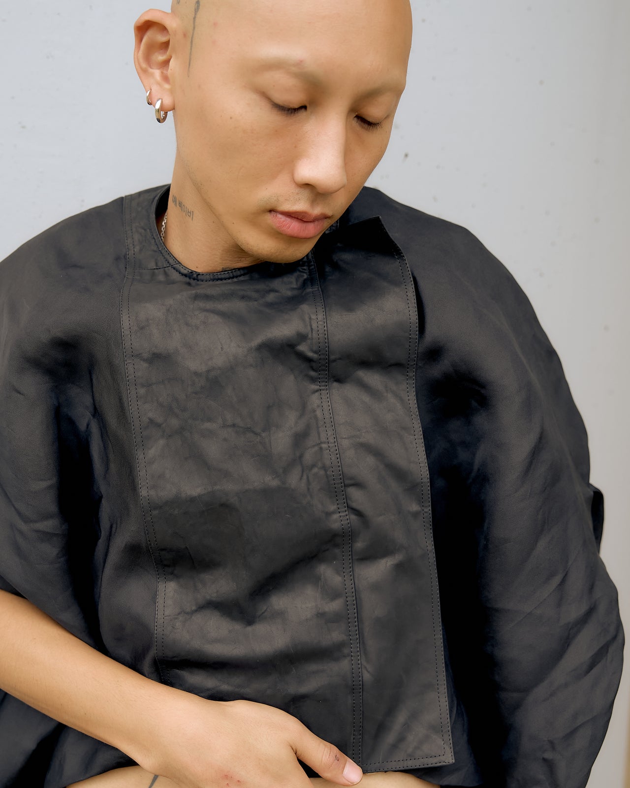 A person wearing a black cropped Rick Owens moto jacket with balloon sleeves and an asymmetric front zip.