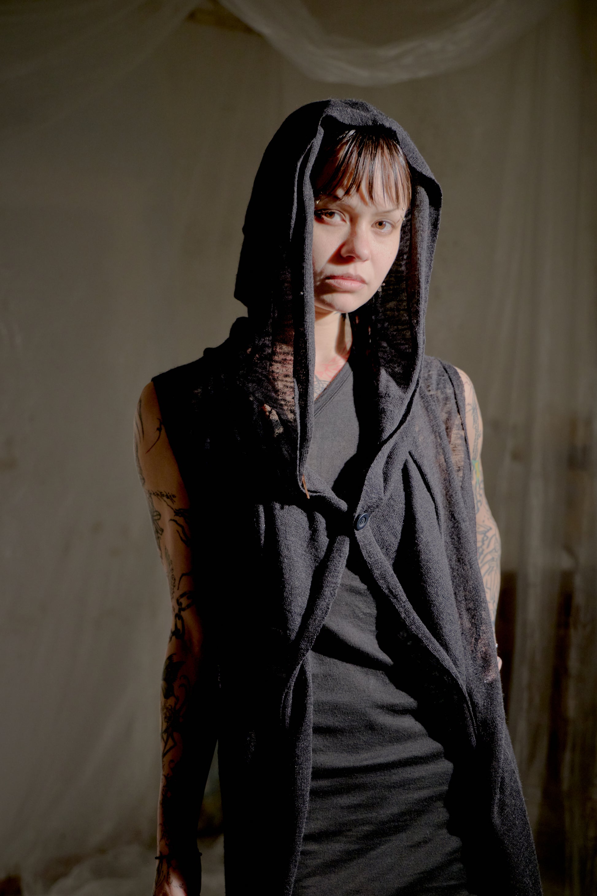 Person wearing a dark hooded Rick Owens garment against a plain background