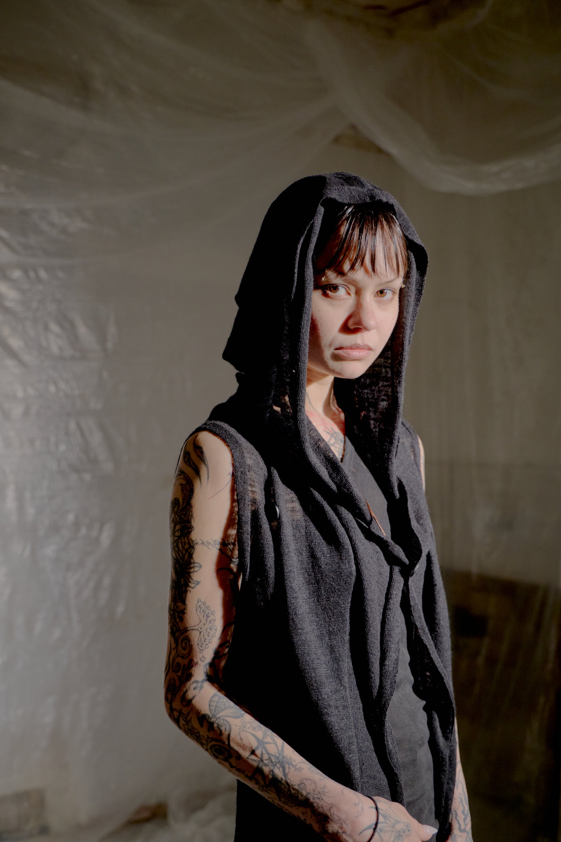 Person wearing a dark Rick Owens hoodie in a dimly lit room