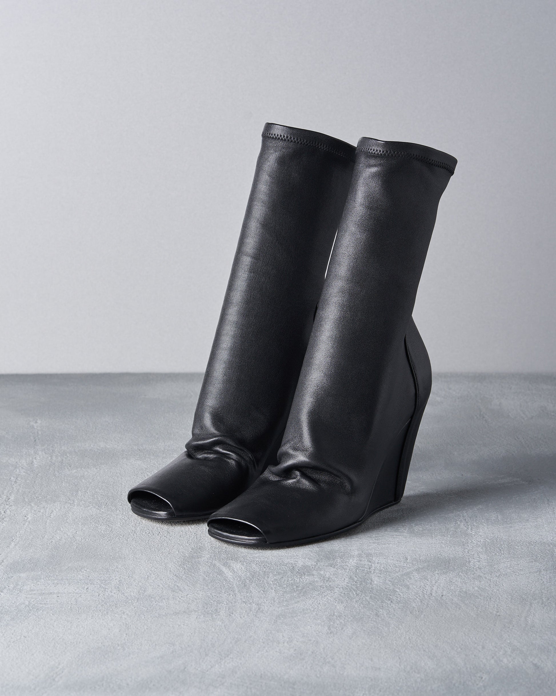 Pair of black leather Rick Owens high boots on a gray background