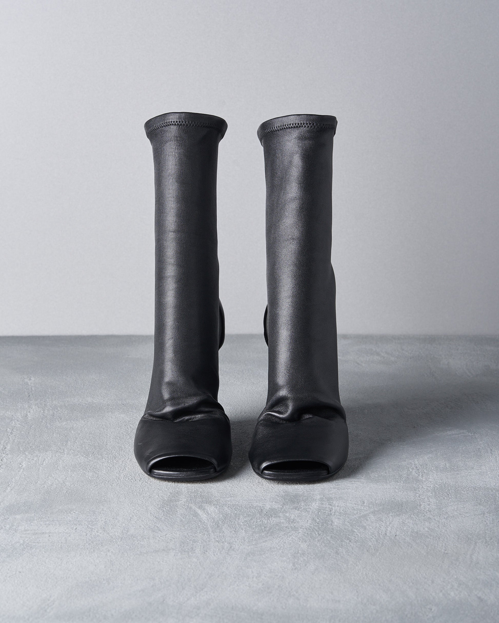 Pair of black Rick Owens boots on a gray surface with a light gray background