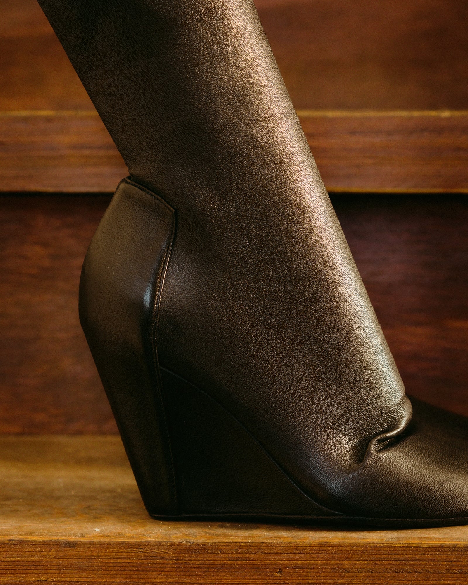 Brown leather Rick Owens wedge heel on a wooden surface with a wooden background