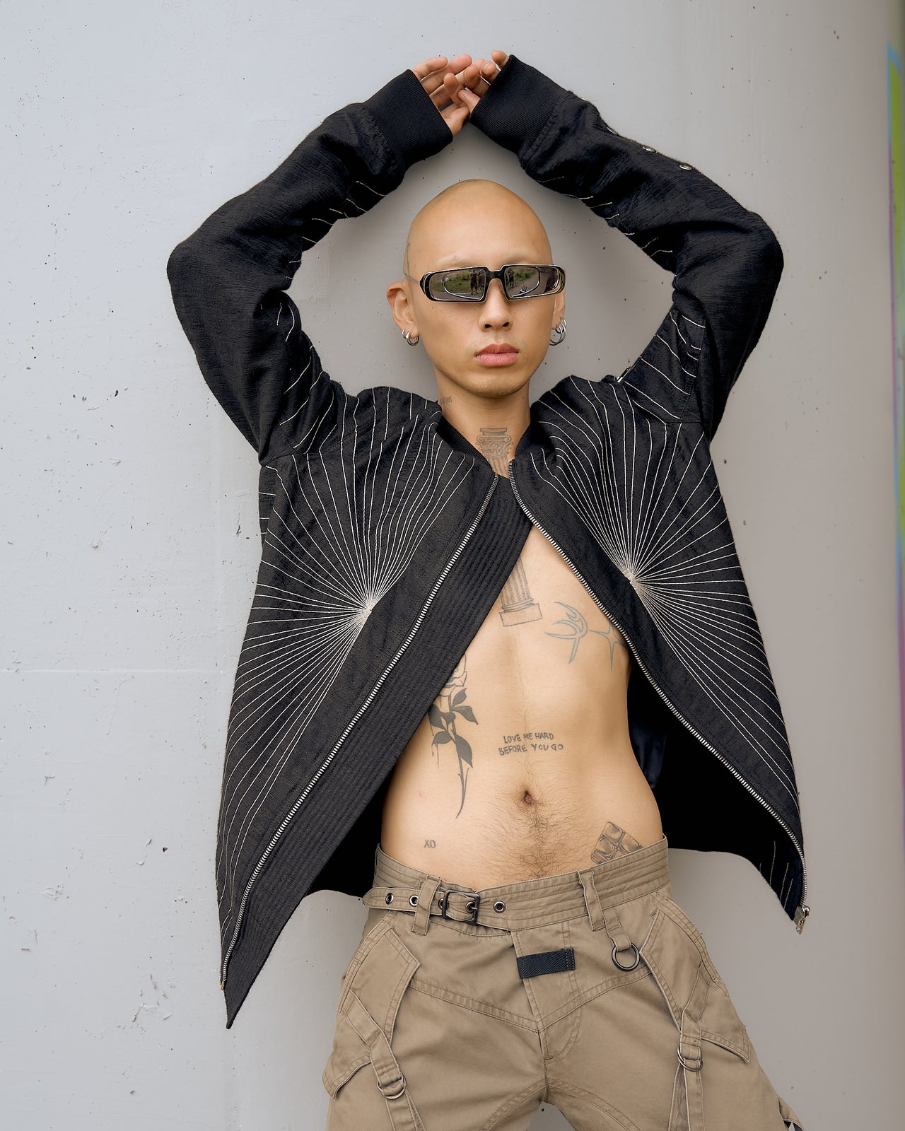 A person wearing a longline Rick Owens bomber jacket with a textural weave and thin chainstitched rays, featuring a chunky front zip and ribbed collar.