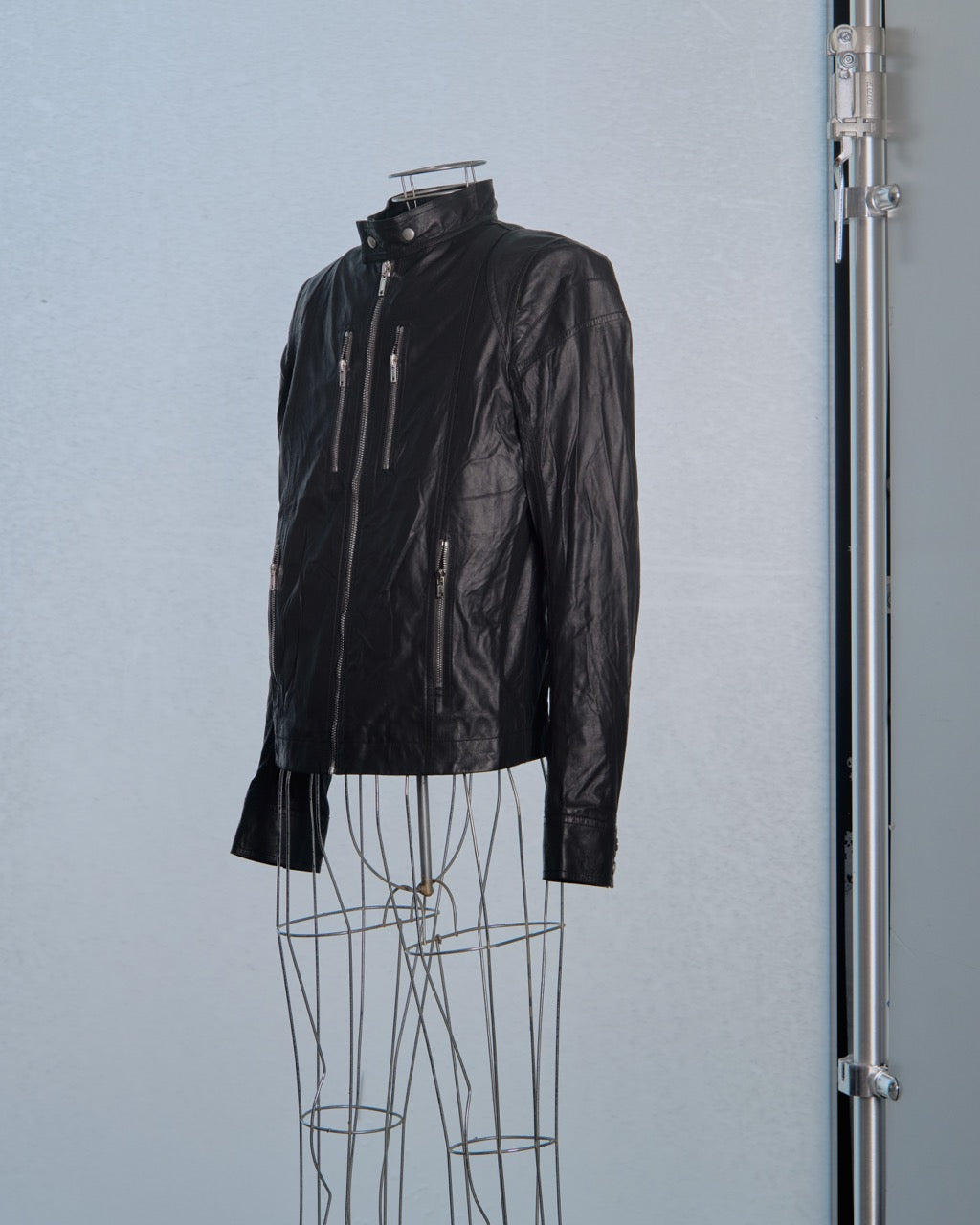 Black leather Rick Owens jacket on a mannequin against a light blue background