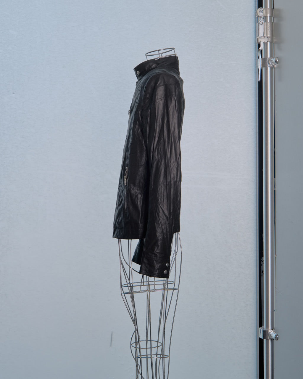 Black leather Rick Owens jacket on a mannequin against a light blue wall