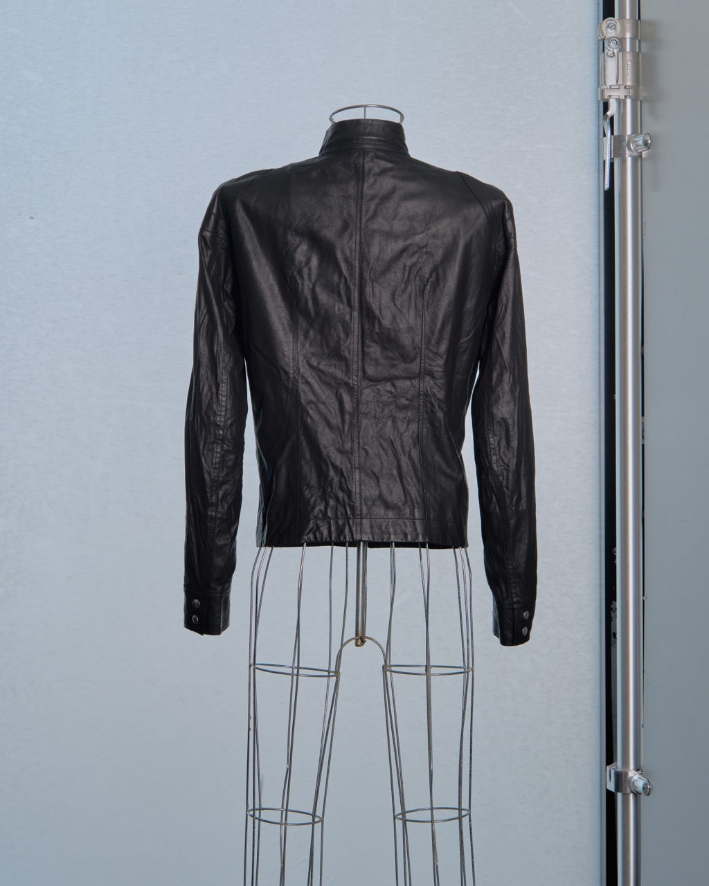 Black leather Rick Owens jacket on a wire mannequin against a light blue background