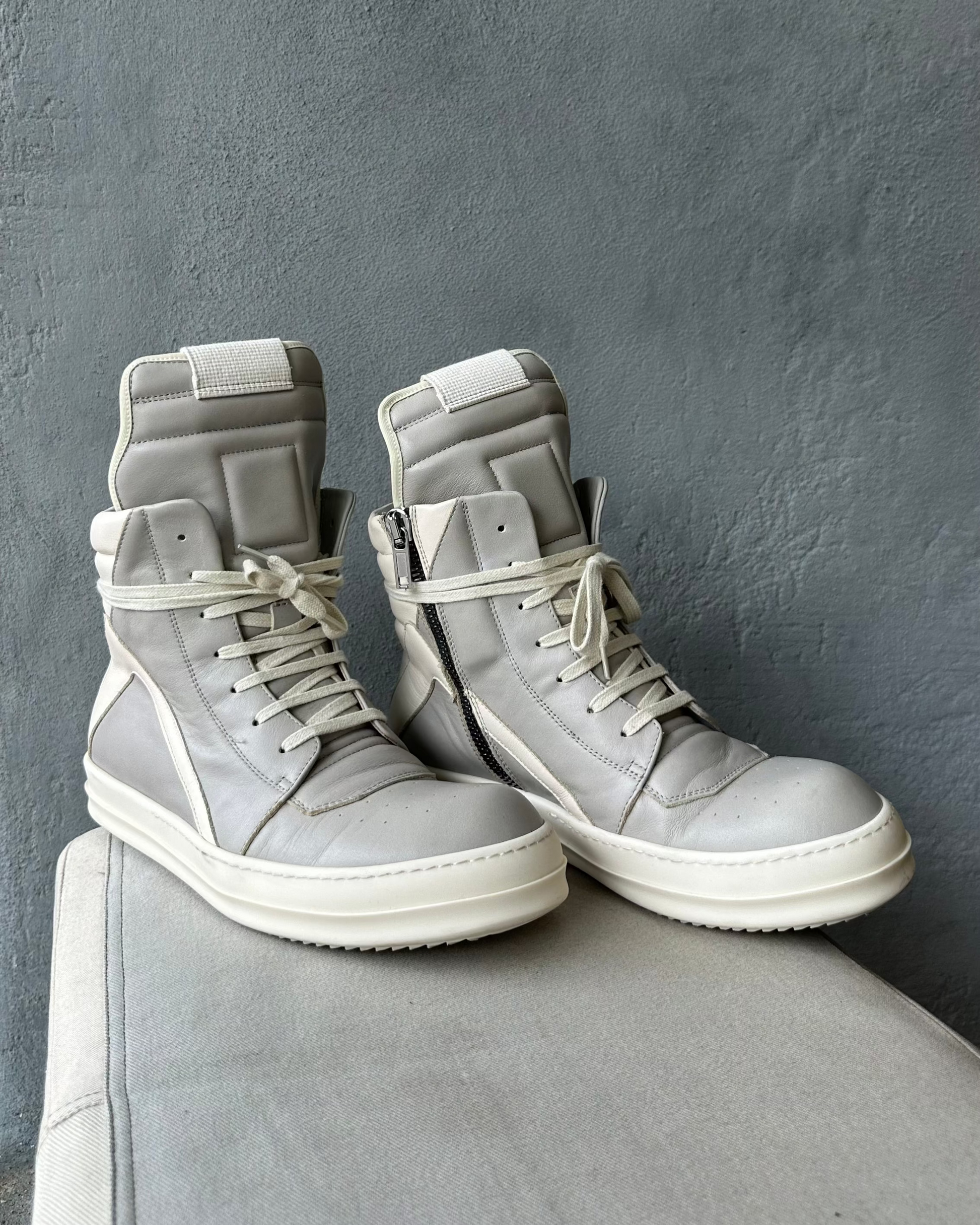 Pair of gray high-top Rick Owens sneakers on a gray surface with a gray background