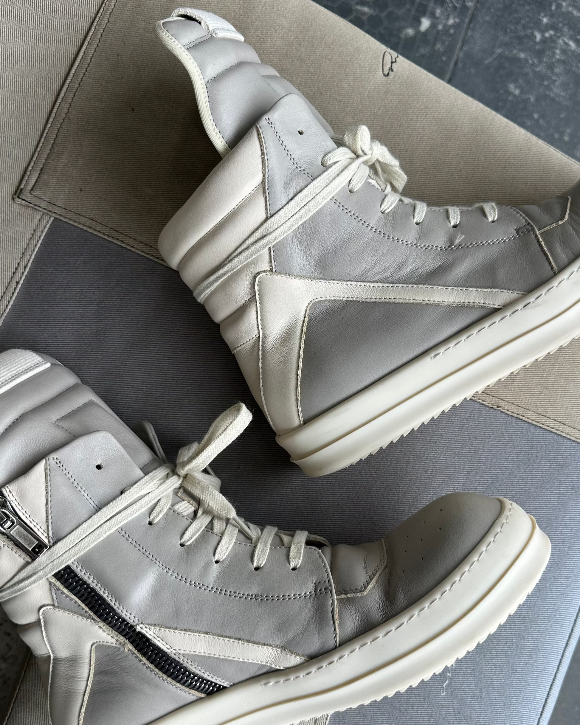 Gray high-top Rick Owens sneakers on a textured surface