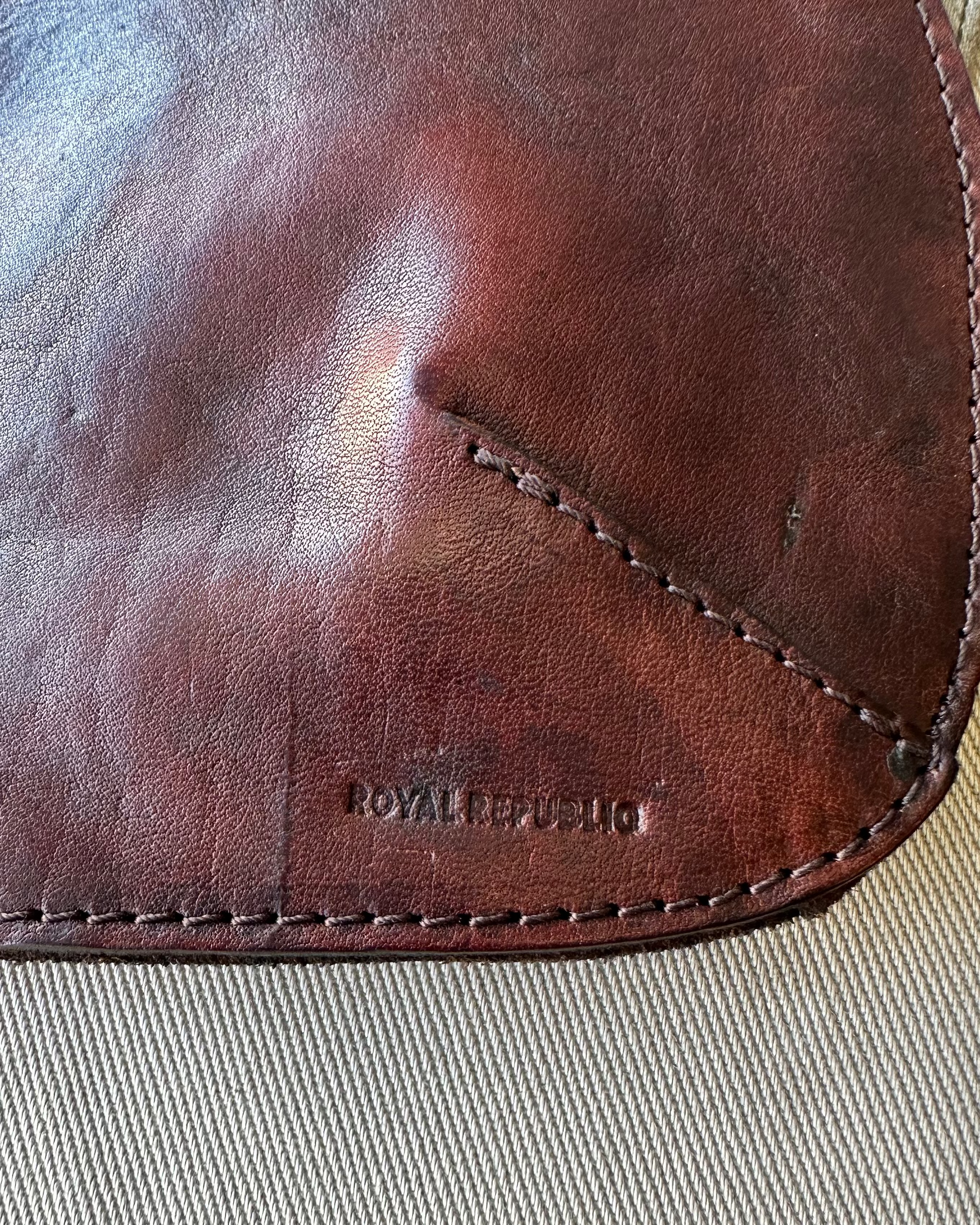 Close-up of a brown leather product with 'Royal Republic' branding on a beige surface.