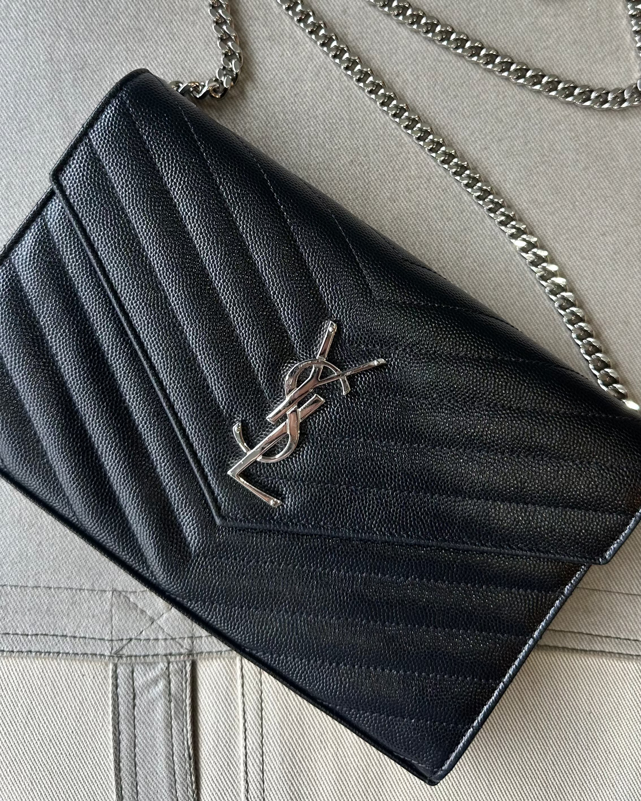 Black quilted Saint Laurent handbag with chain strap on a light gray background
