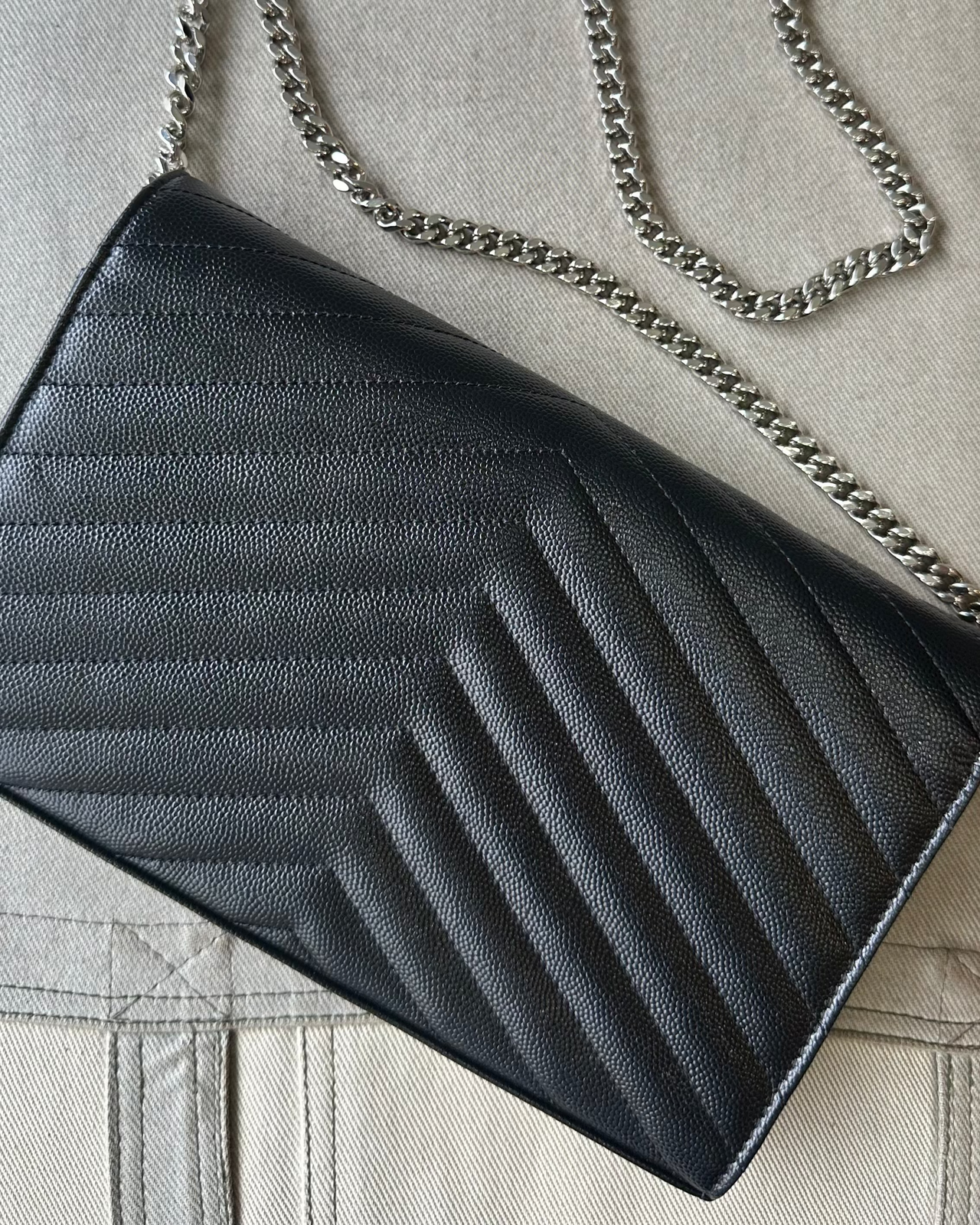 Black quilted Saint Laurent handbag with chain strap on a light gray background